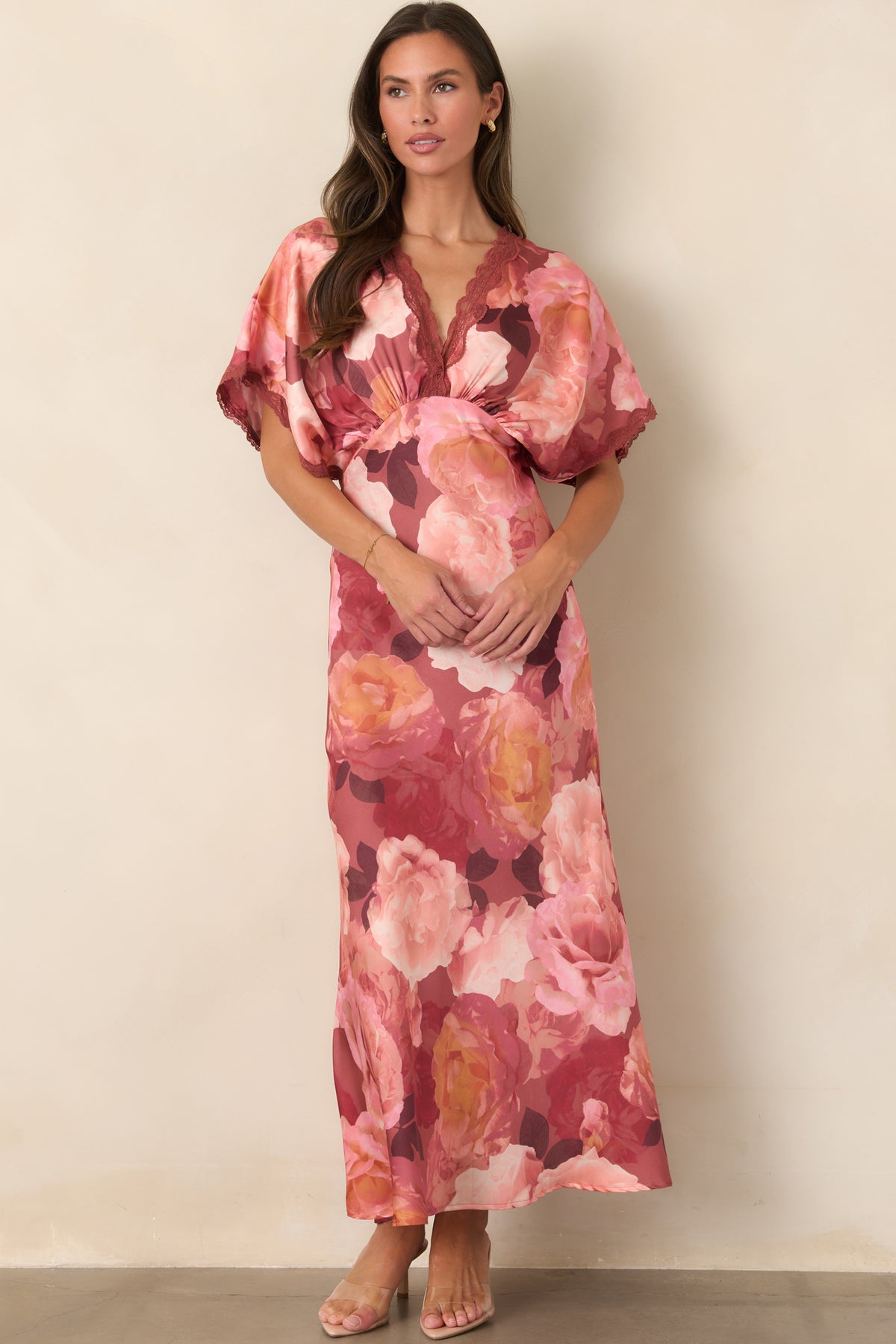 Satin dress with oversized rose and coral florals, flutter sleeves, lace detailing, and a softly flowing floor-length skirt.