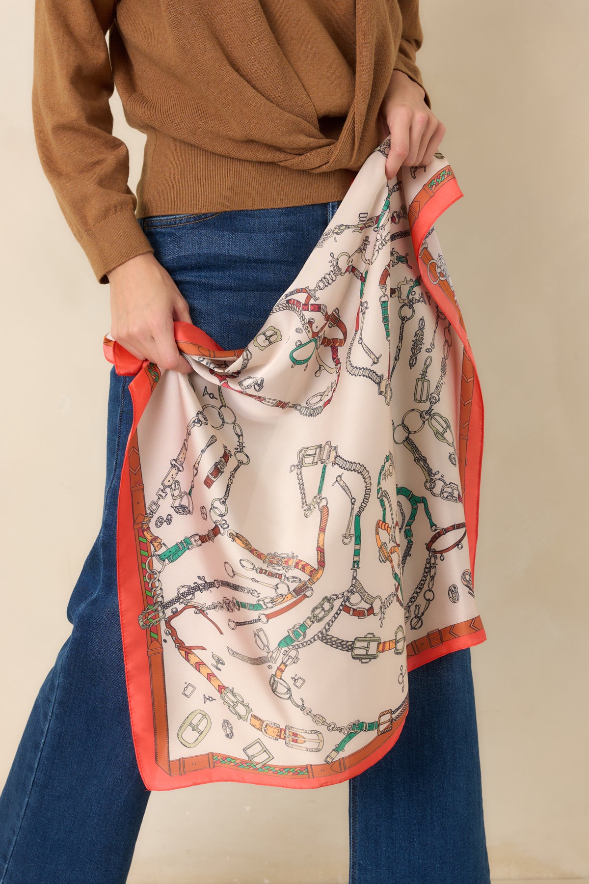Satin scarf features a vivid orange border framing the design, with a smooth finish and fluid drape.