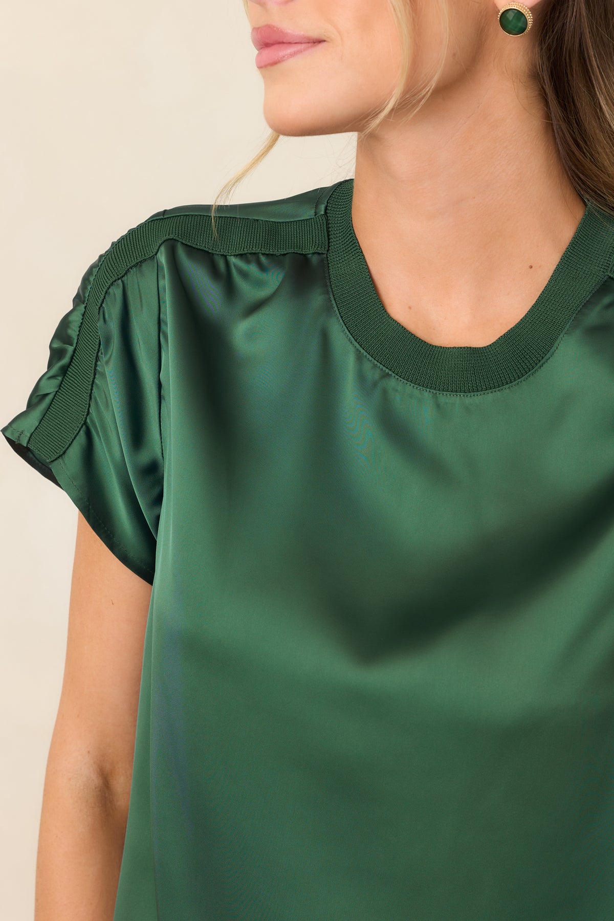 Close view highlighting the smooth satin sheen alongside the contrasting ribbed trim bordering the neckline and shoulder.