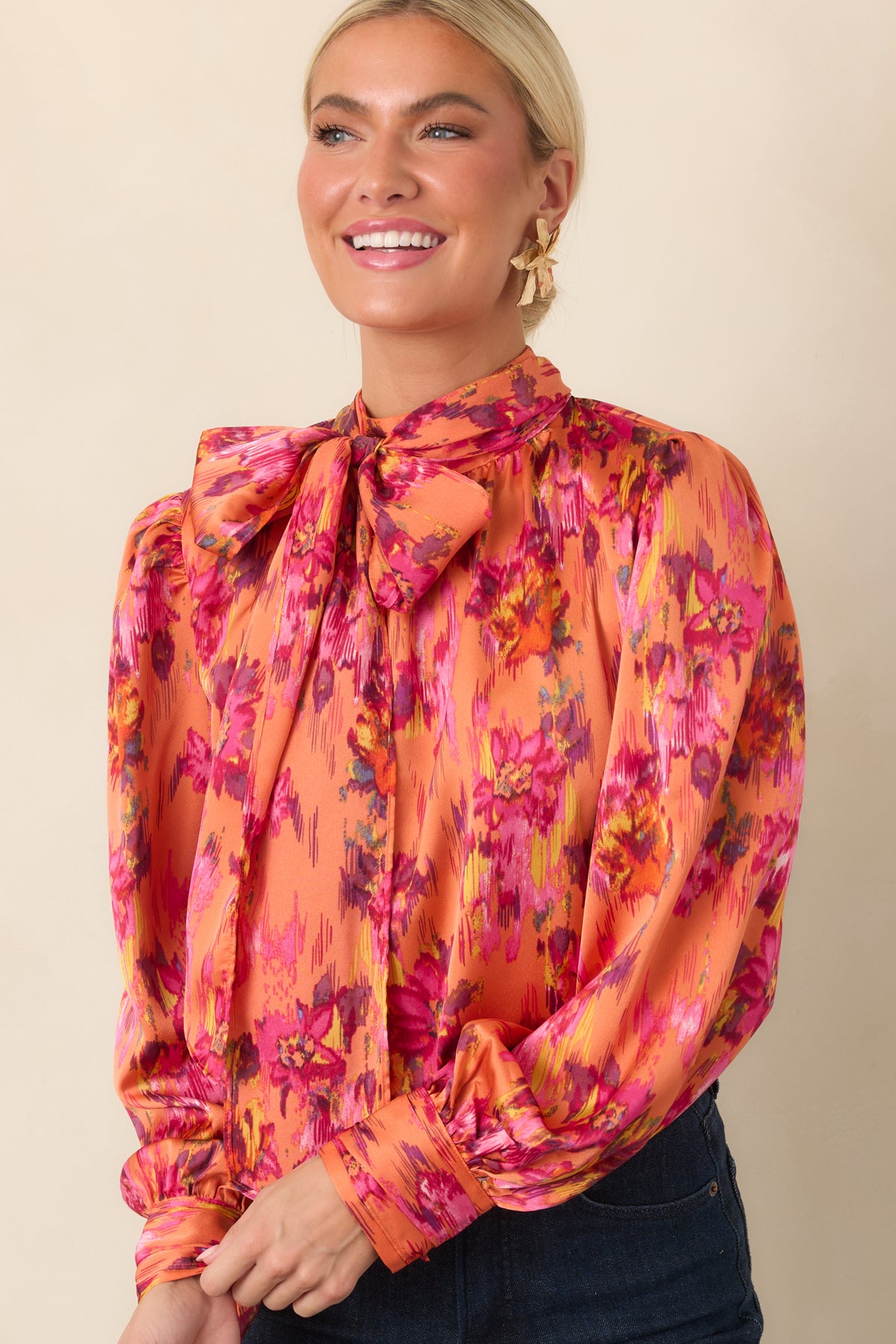 Close view of the blouse highlighting the graceful tie detail at the neckline and softly gathered satin fabric across the shoulders.