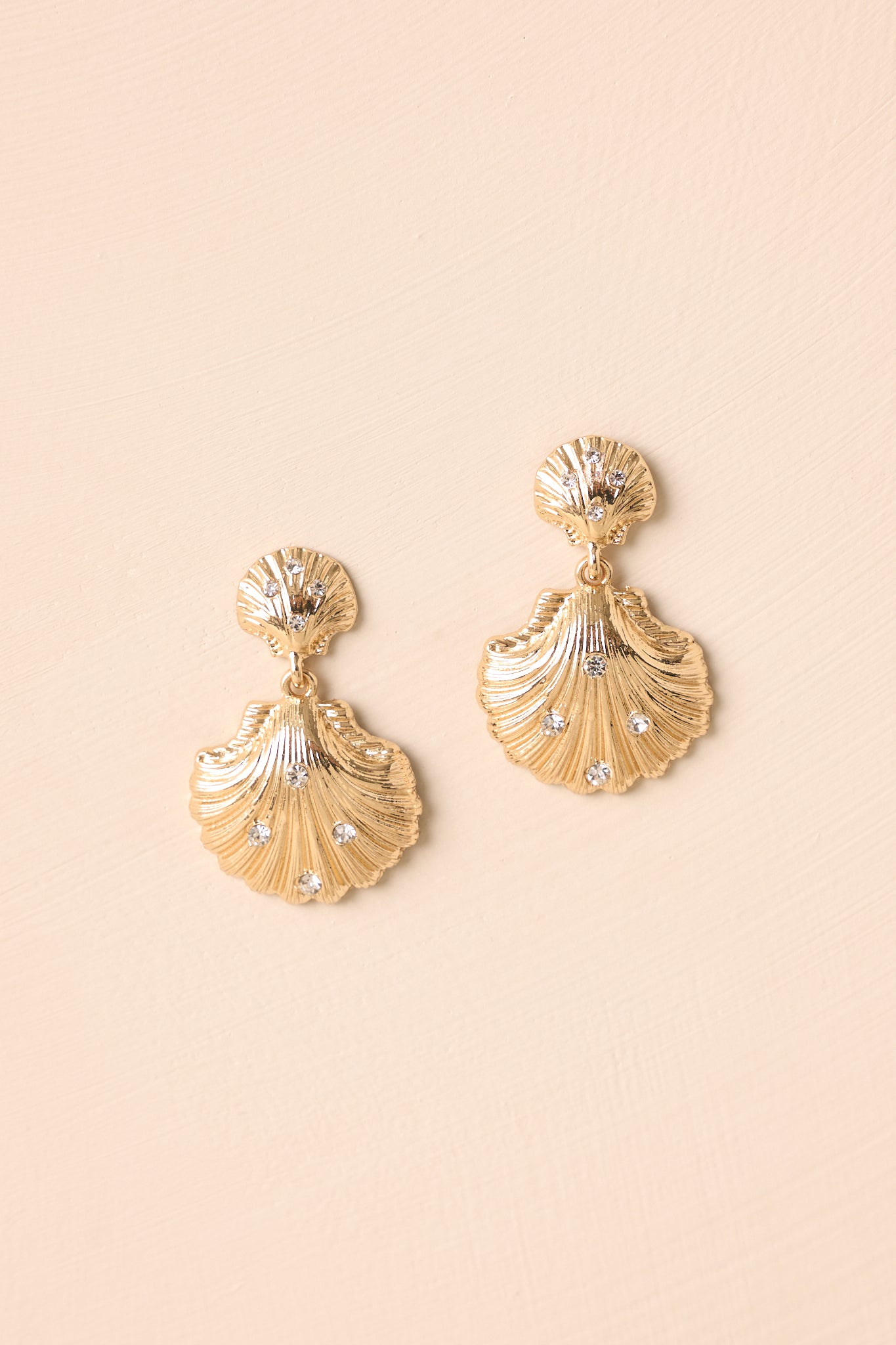 Zoomed-in view of the top scallop stud and rhinestones of a gold earring, emphasizing the intricate shell pattern and sparkle.
