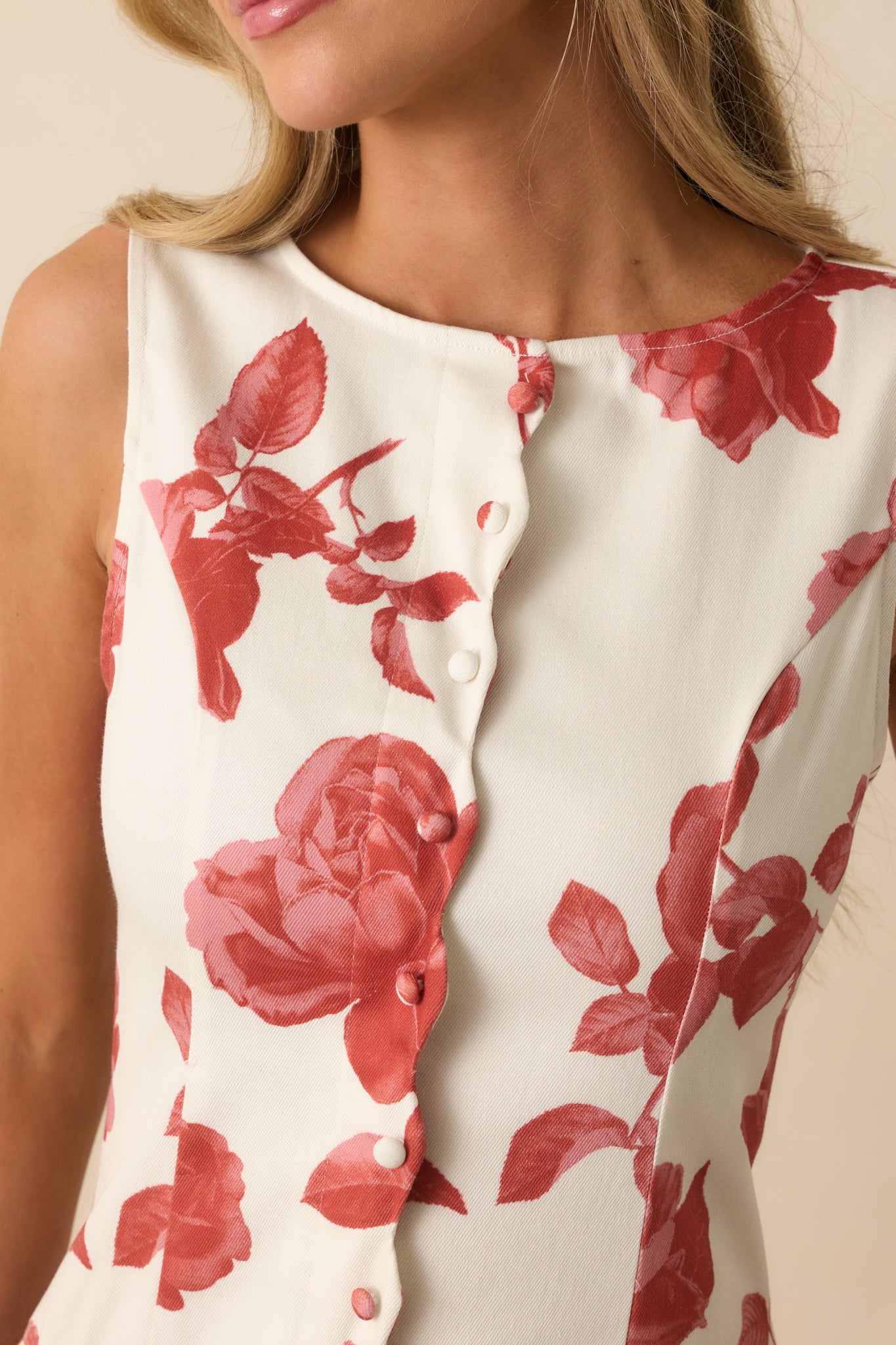 Detailed view of the scallop trim placket, faux buttons, and brick red floral print on the ivory dress.