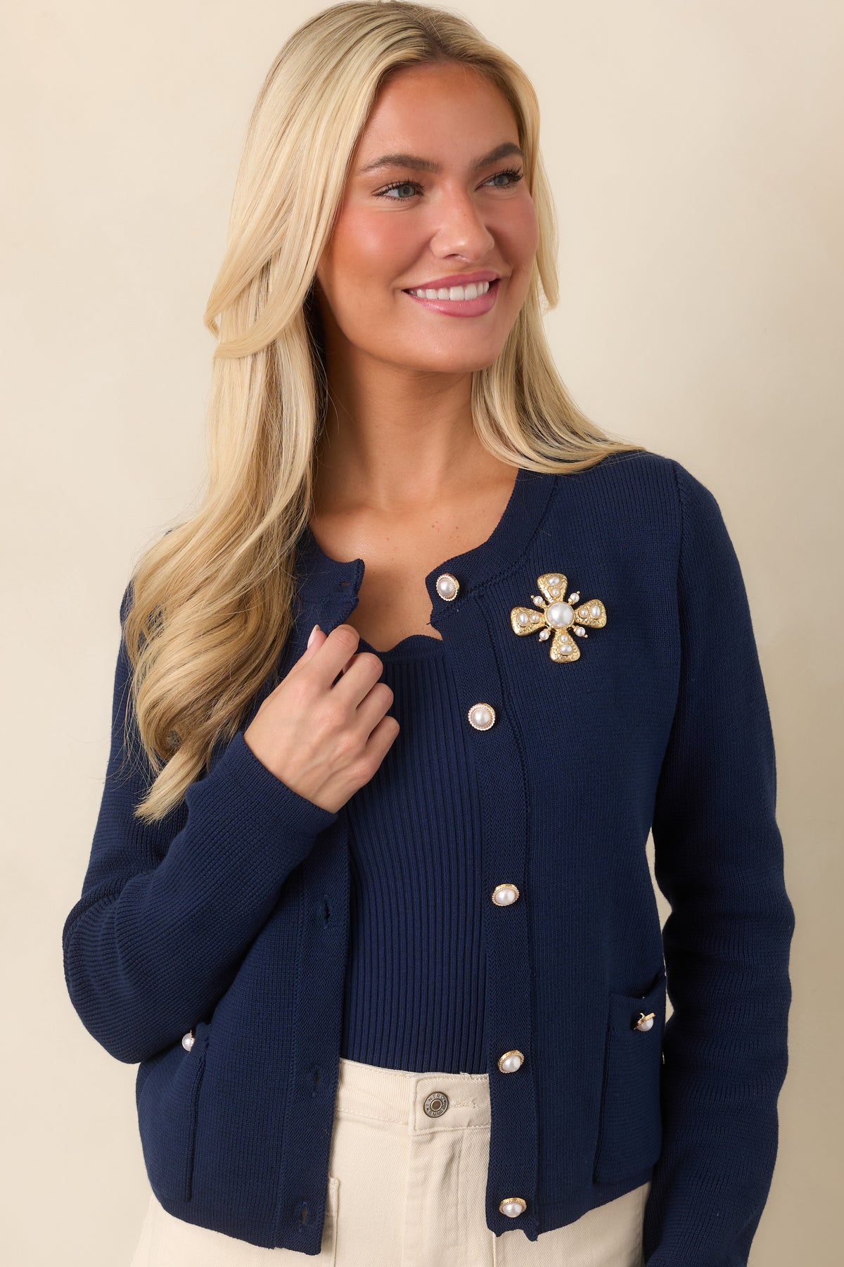 Close view of the cardigan highlighting its crew neckline, scalloped trim, and pearl-inspired buttons with gold-tone accents.