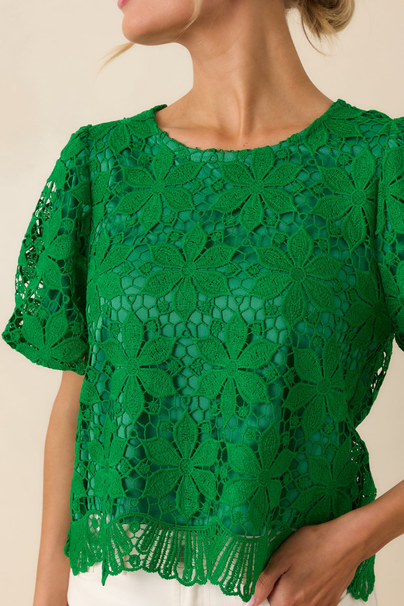 Scalloped hem and floral crochet lace texture on green fabric.