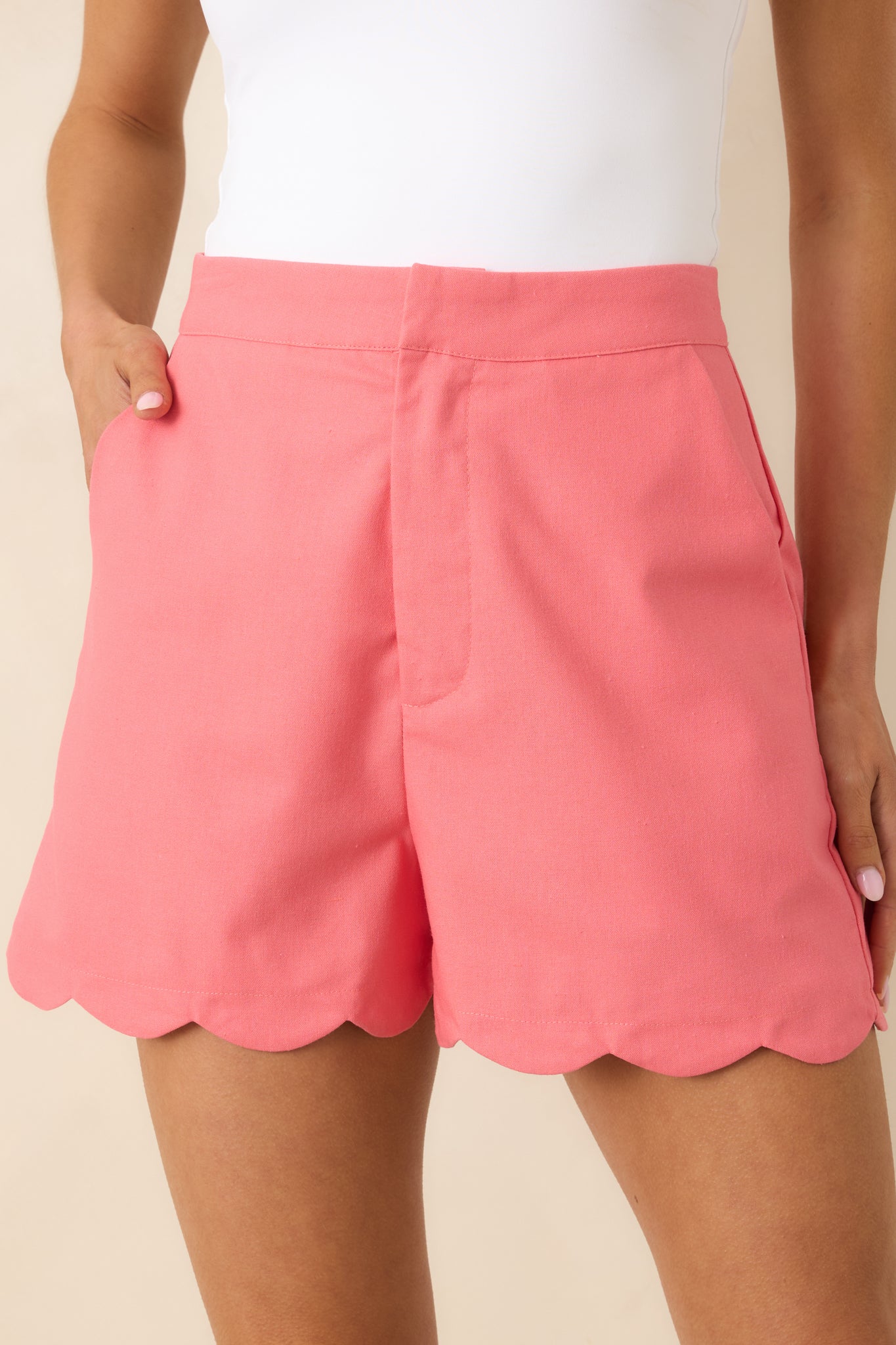 Scalloped hem detail on coral shorts with structured stitching