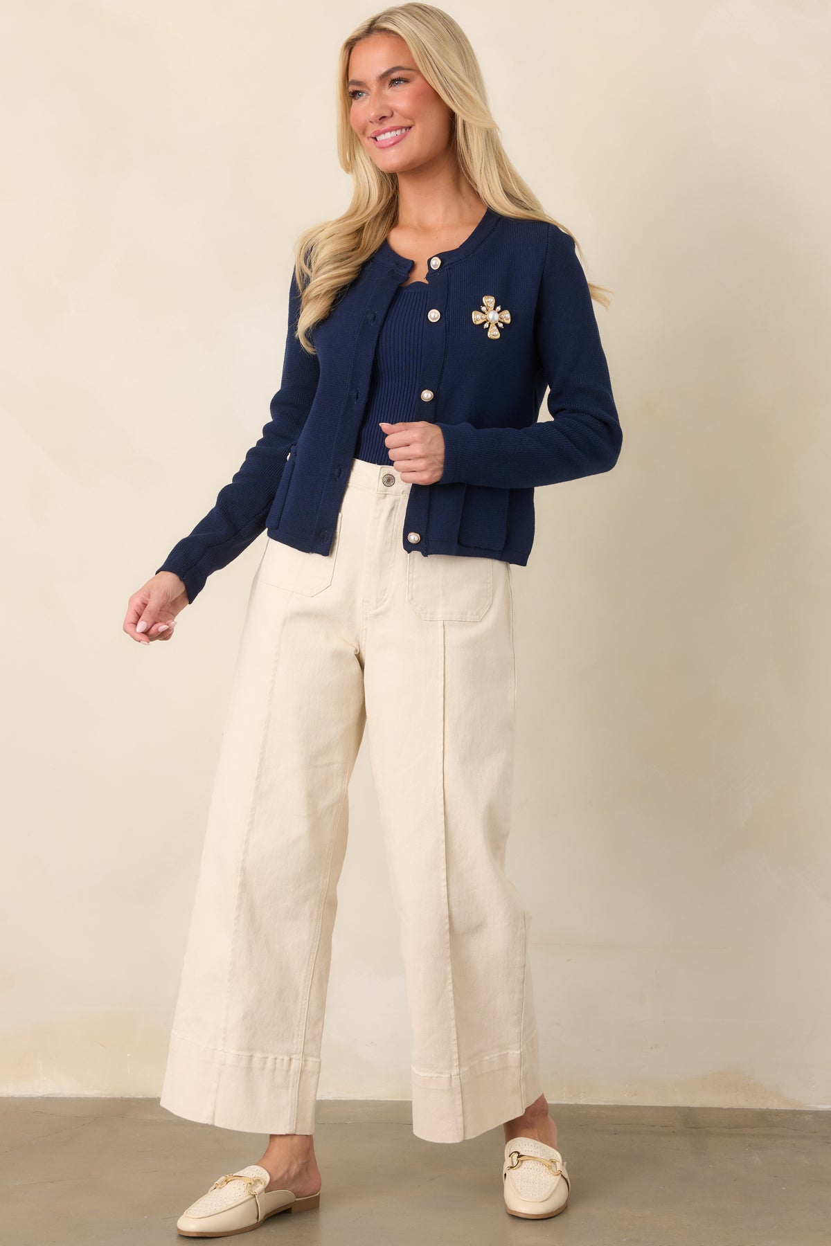 Refined cotton cardigan showcasing long sleeves, front patch pockets, scalloped neckline trim, and decorative pearl-style buttons.