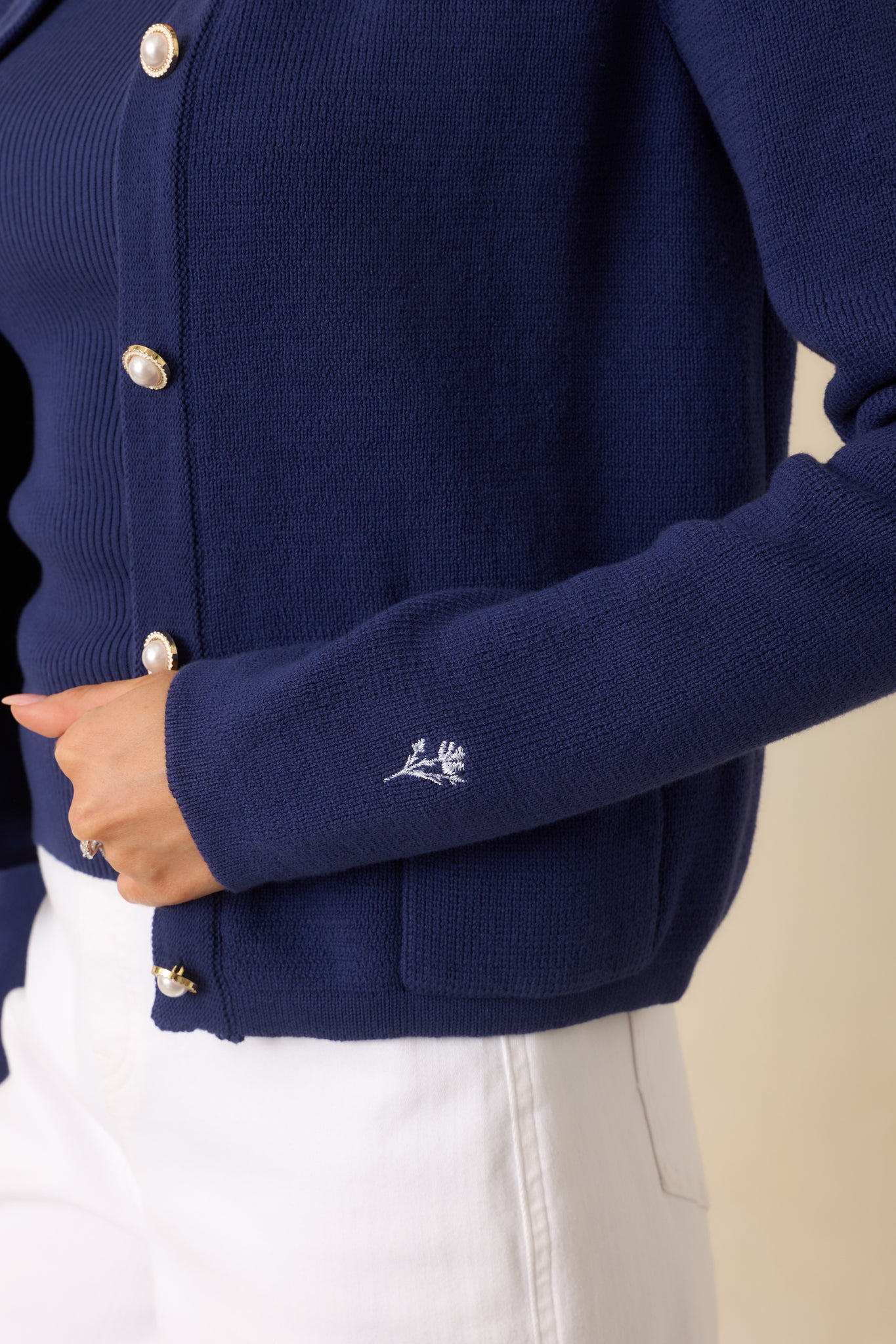 Close-up view of the scalloped neckline detail framed by elegant pearl-inspired buttons.