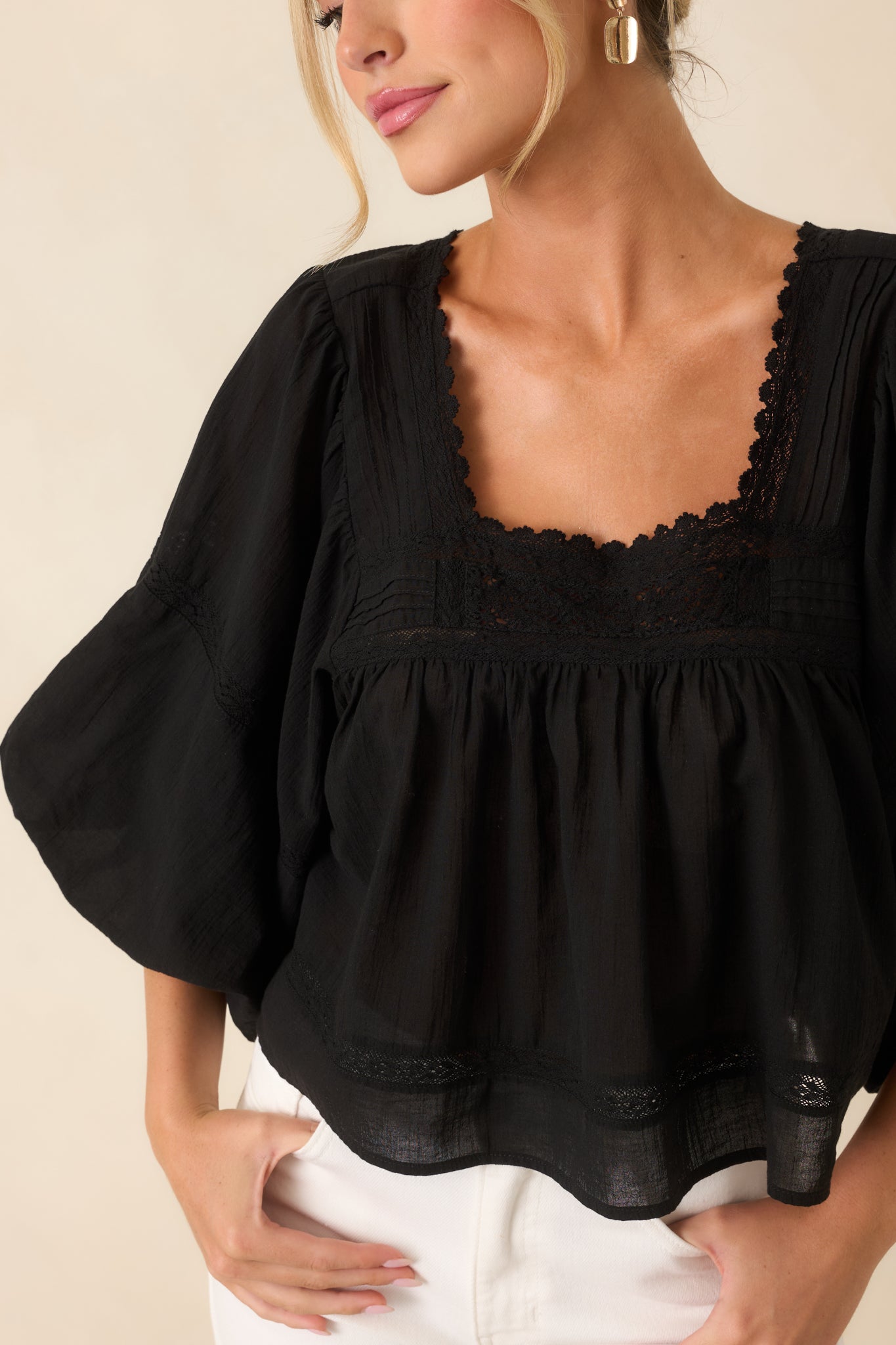 Close-up highlighting the scalloped trim, lace inset detailing, and softly gathered square neckline of the cotton blouse.
