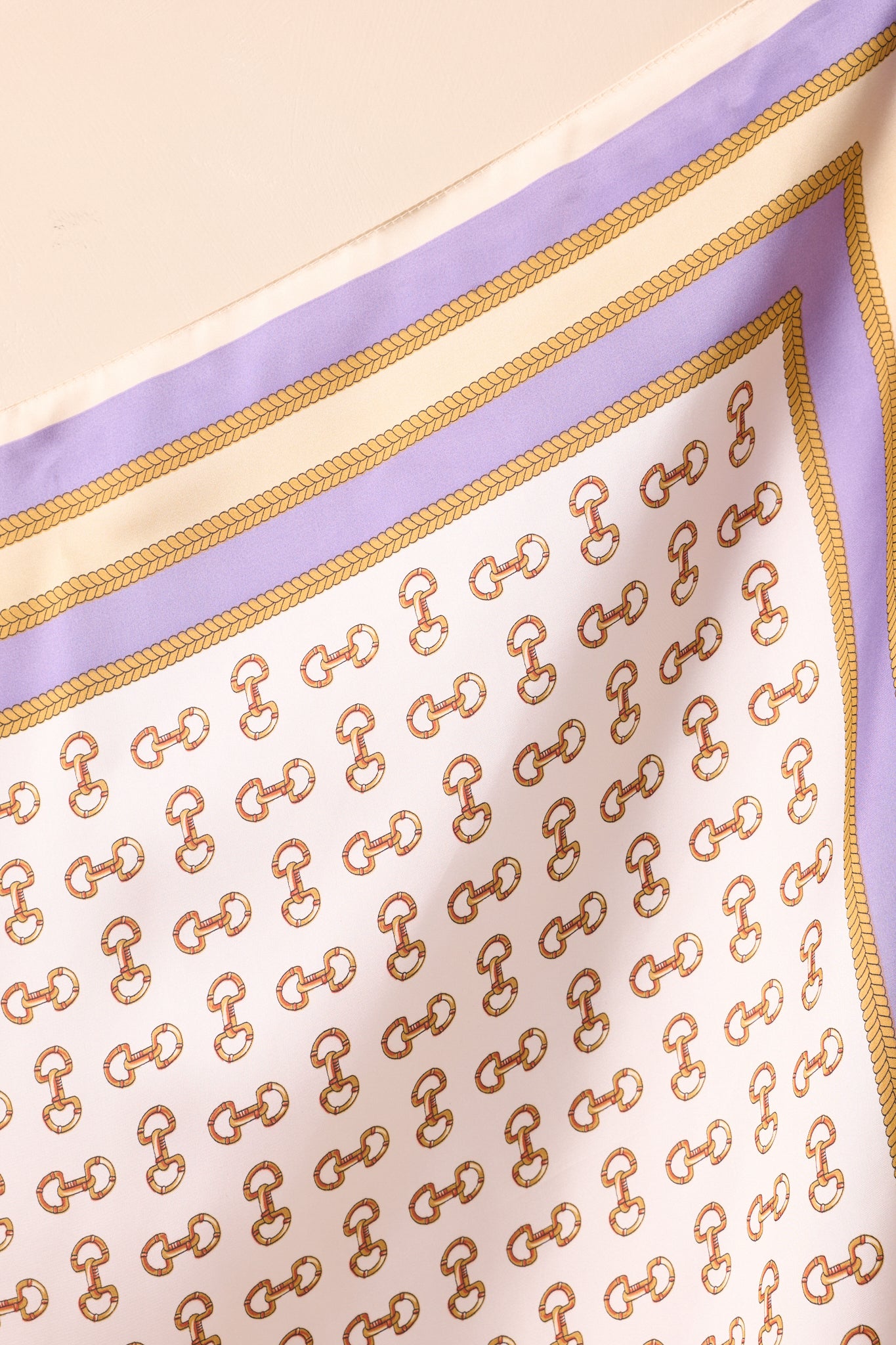 Close-up of the scarf, emphasizing the satin finish, gold snaffle bit motifs, and chain border detailing.