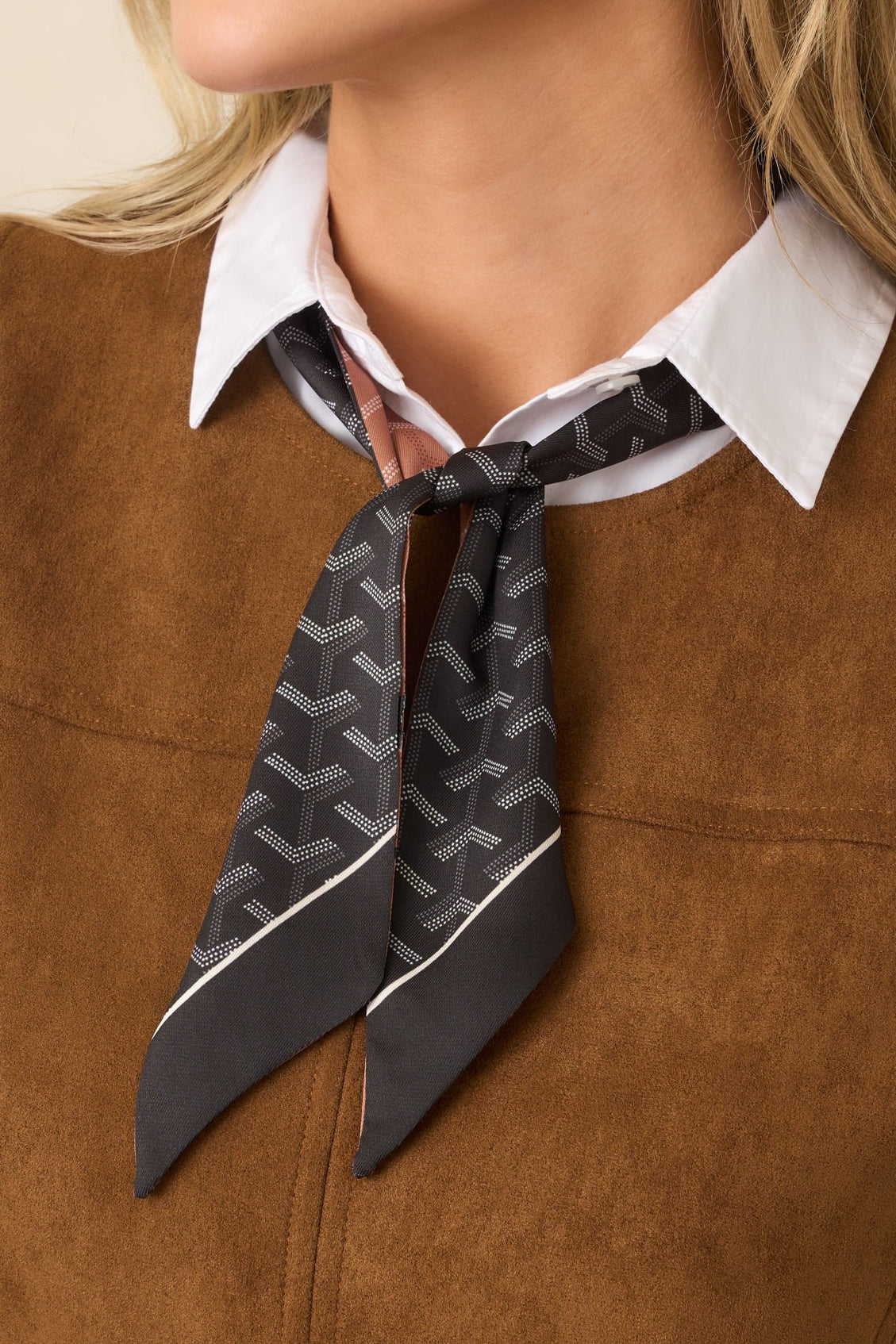 Close-up of the scarf showing its geometric print and crisp contrast border.
