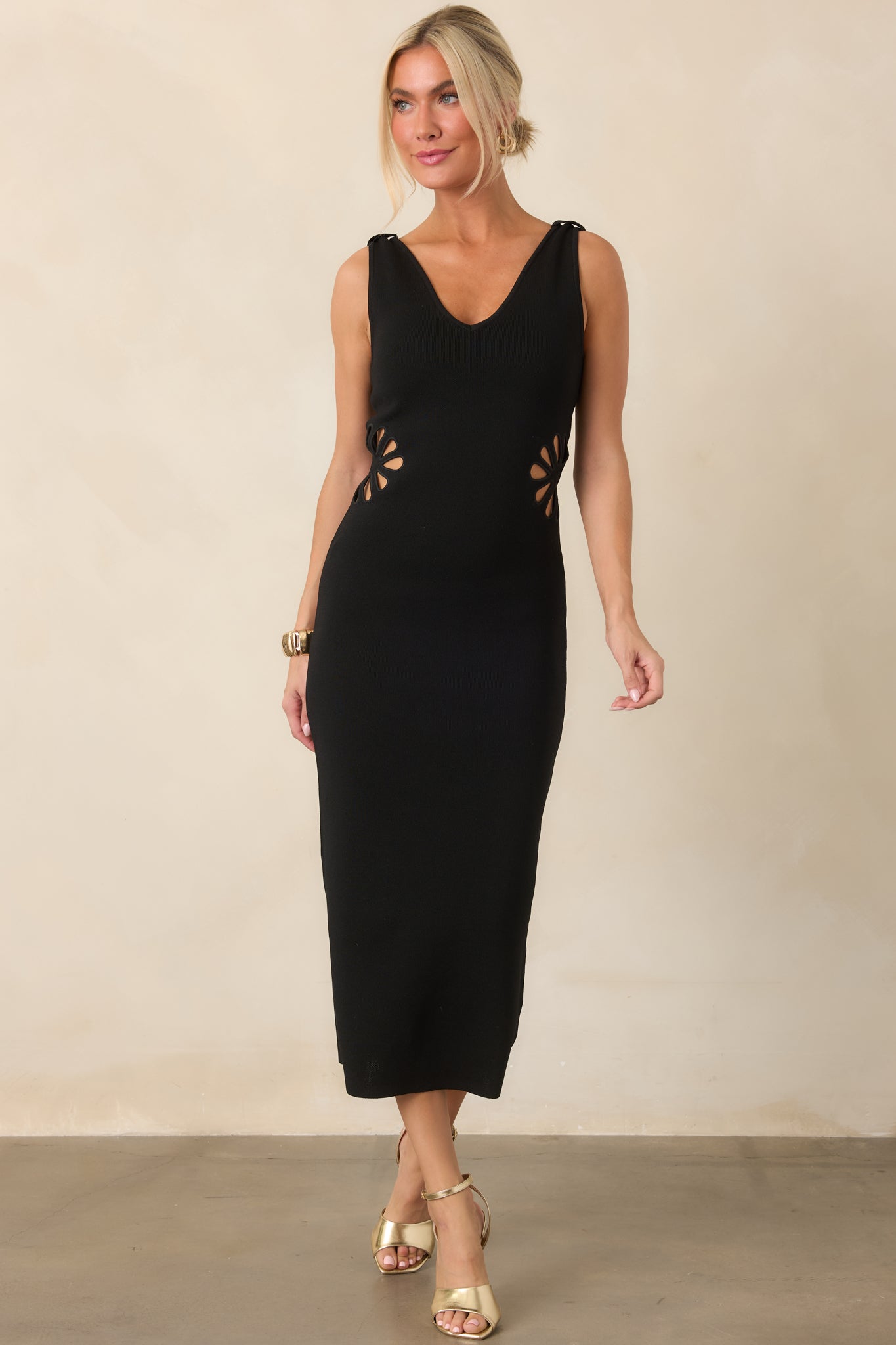 Pullover midi dress showcasing a sculpted knit silhouette, wide shoulder straps, and symmetrical floral-inspired openings at the waist.