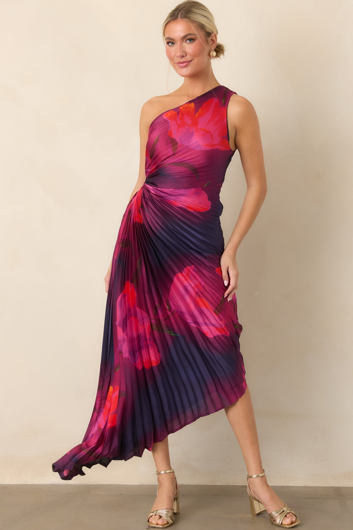 Sculpted pleats shape the floral dress, while waist ruching emphasizes the cutout detail above the flowing asymmetrical hem.