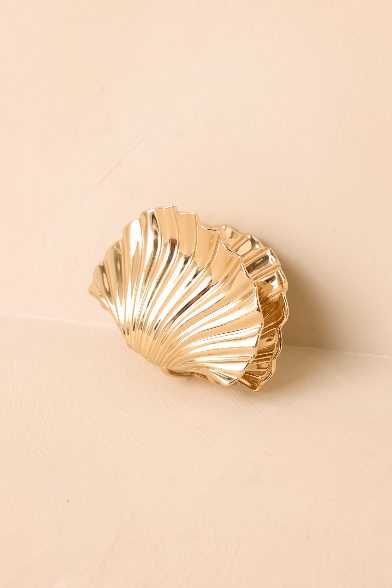 Sculptural gold hair accessory highlighting the curved silhouette and polished metallic surface.