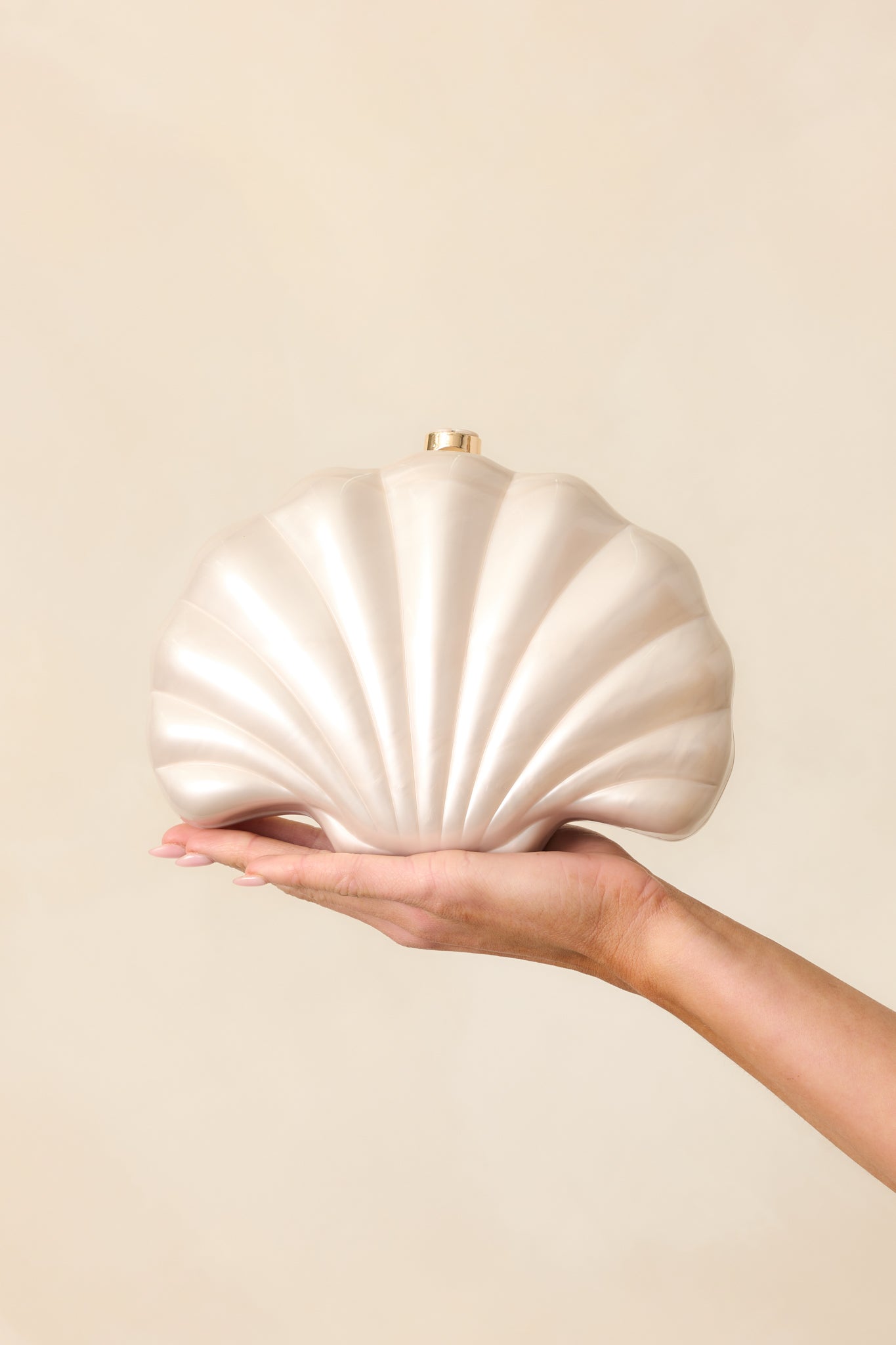 Add a touch of elegance with this seashell-shaped clutch featuring an ivory pearlescent finish, magnetic clutch closure, and an optional crossbody chain for versatile wear.