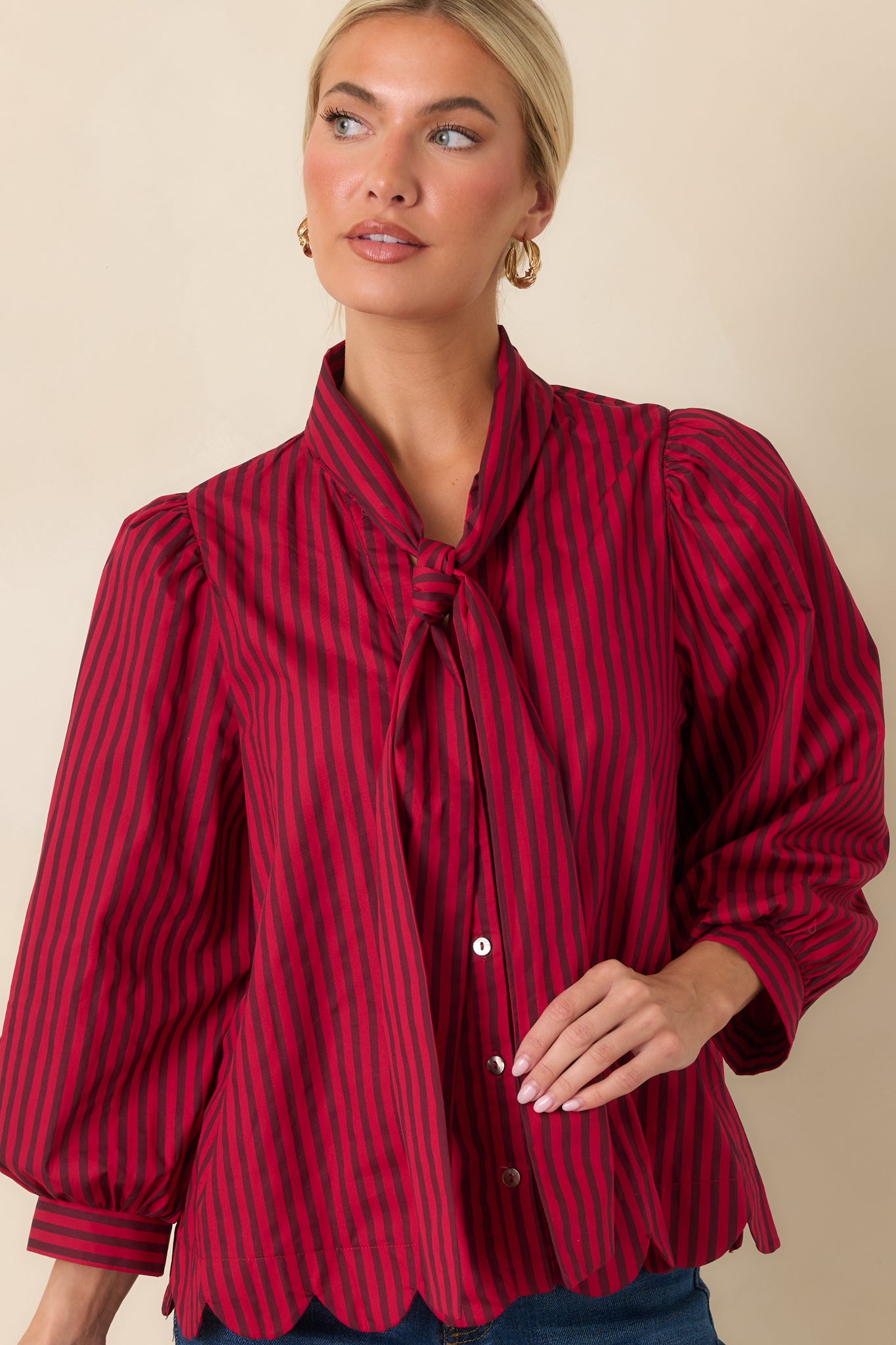 Close view of the self-tie neckline and candy red striped pattern on the cotton blouse.