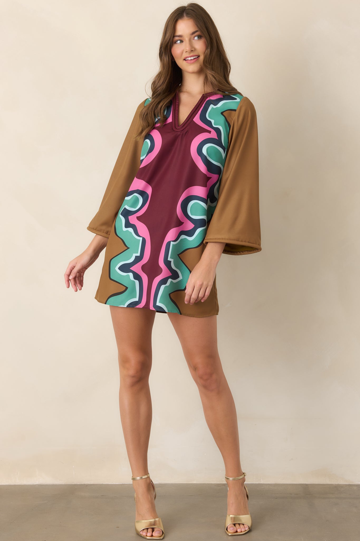Serpentine-print mini dress featuring a soft corded V-neckline, wide three-quarter sleeves, matching trim, and a relaxed A-line silhouette in vibrant multicolored tones.