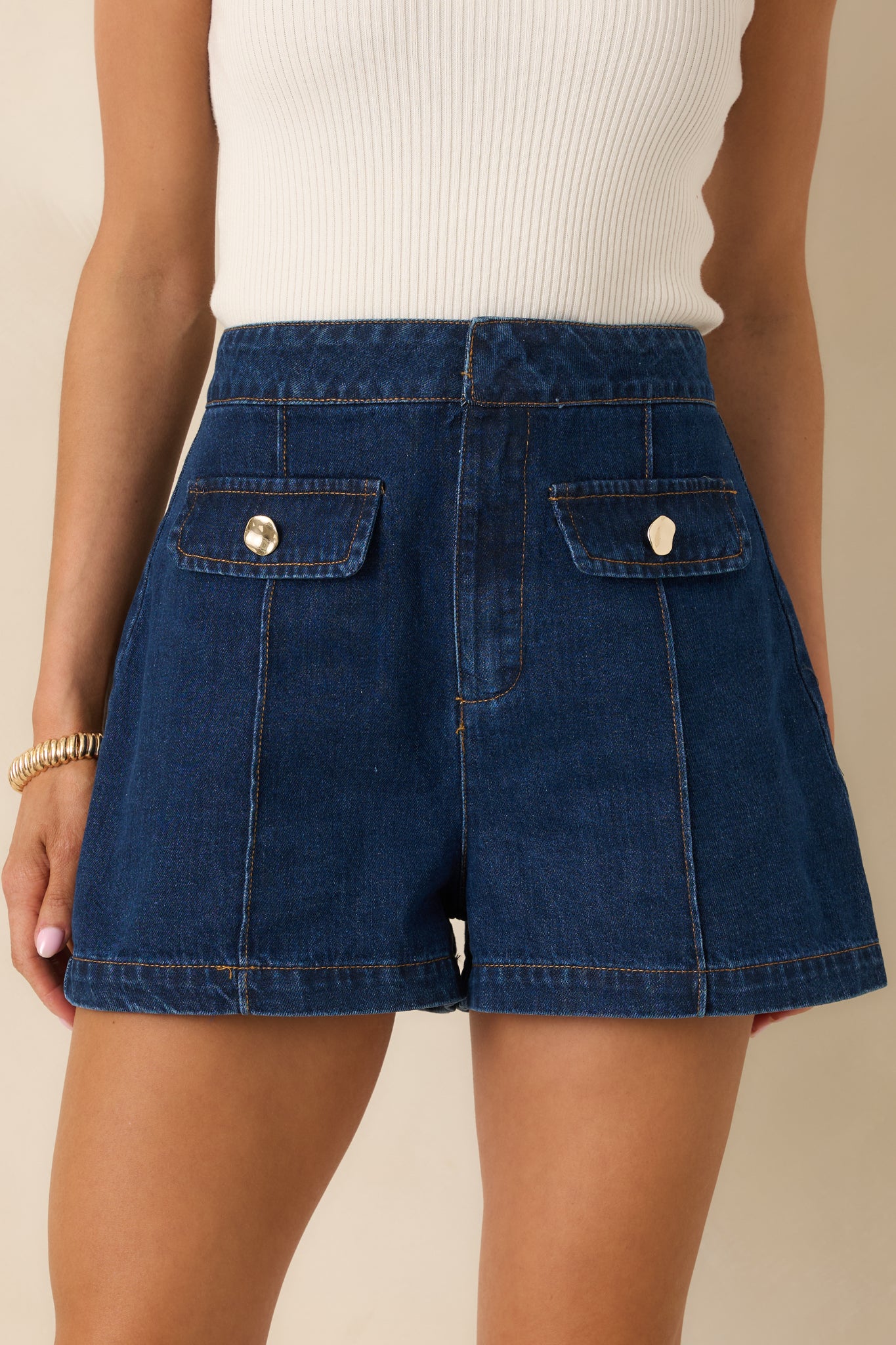 Sewn-in front pleats adding shape to indigo denim shorts.