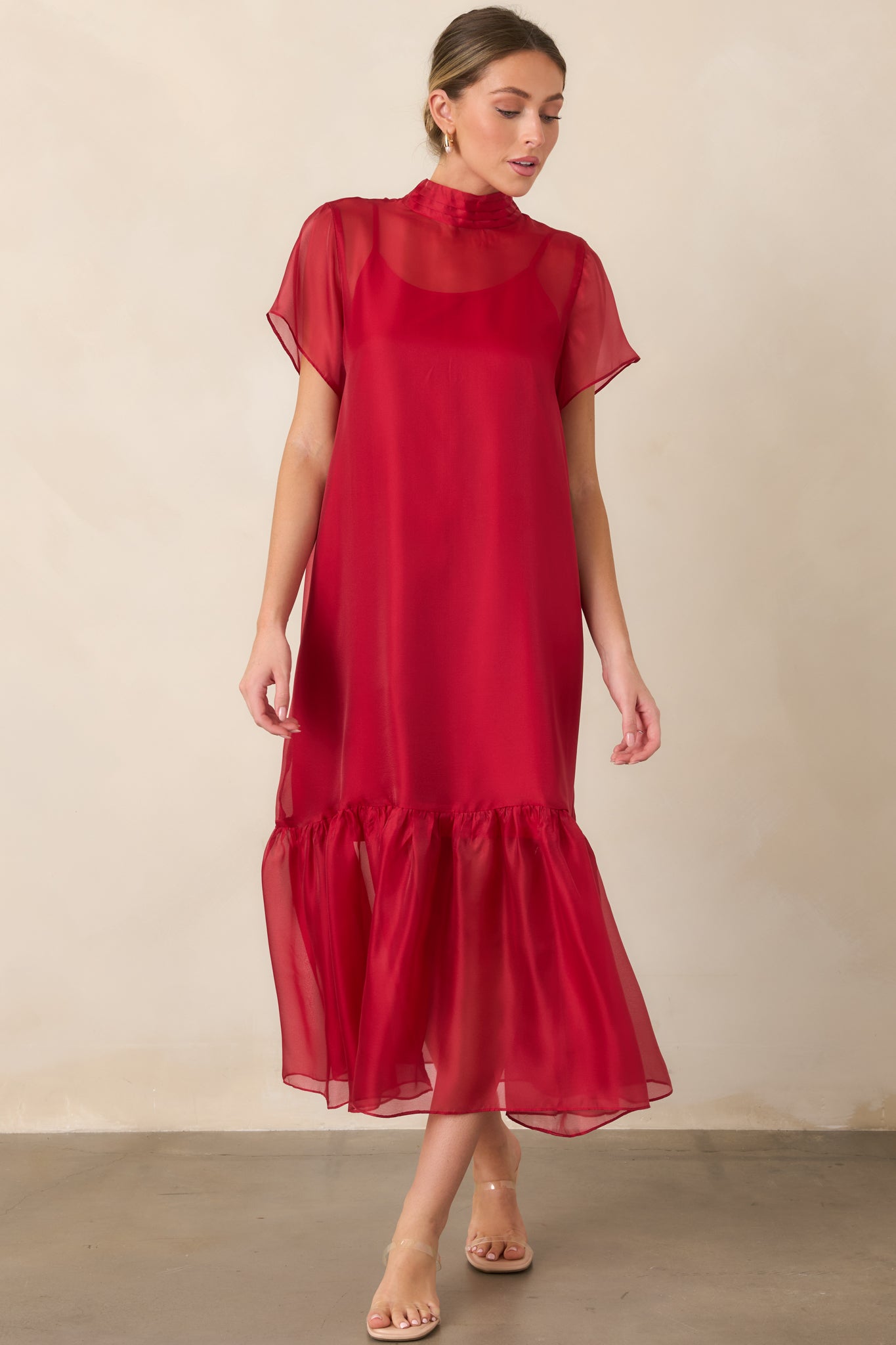 Elegant sheer maxi dress with a smooth slip lining, structured mock neck, delicate short sleeves, and a flowing ruffled hem for added movement.