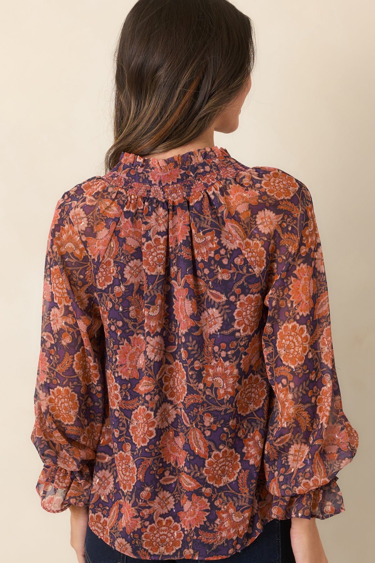 Rear of the sheer floral top showing the multicolor overlay and long sleeves with ruffled cuffs.