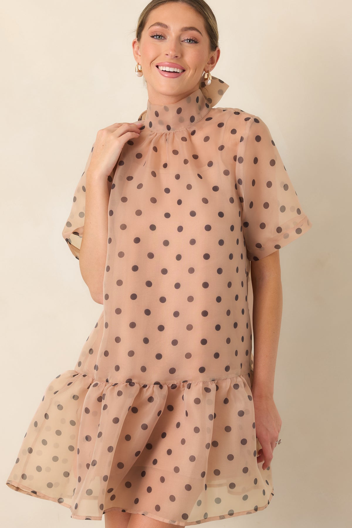 Sheer organza mini dress showcasing the black polka dots and gathered ruffle trim along the hem.