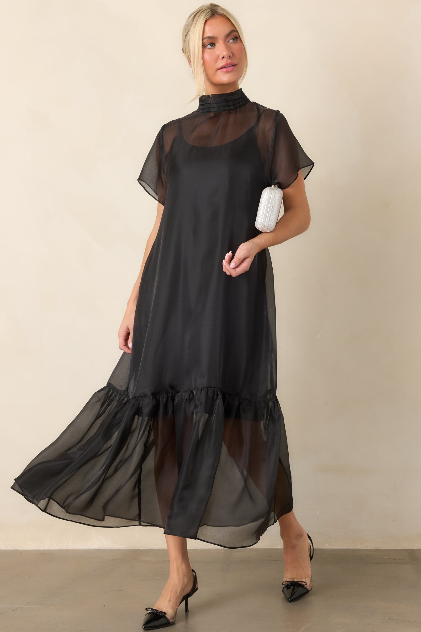 Sheer organza maxi dress layered over a coordinating slip lining, featuring a pleated mock neckline, short sheer sleeves, and a gathered ruffle hem.