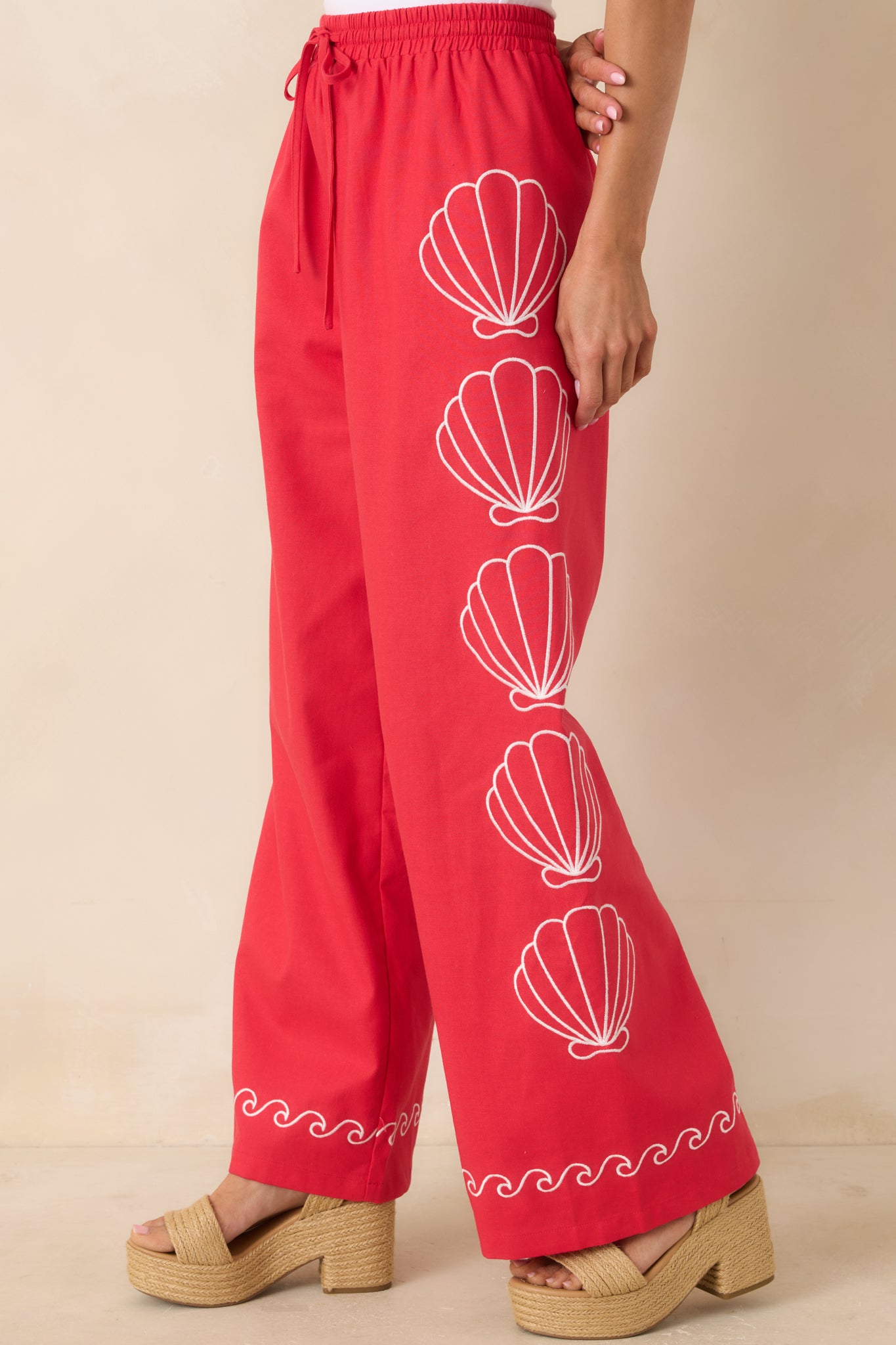 Shell embroidery and contrast wave trim on soft red cotton blend fabric.