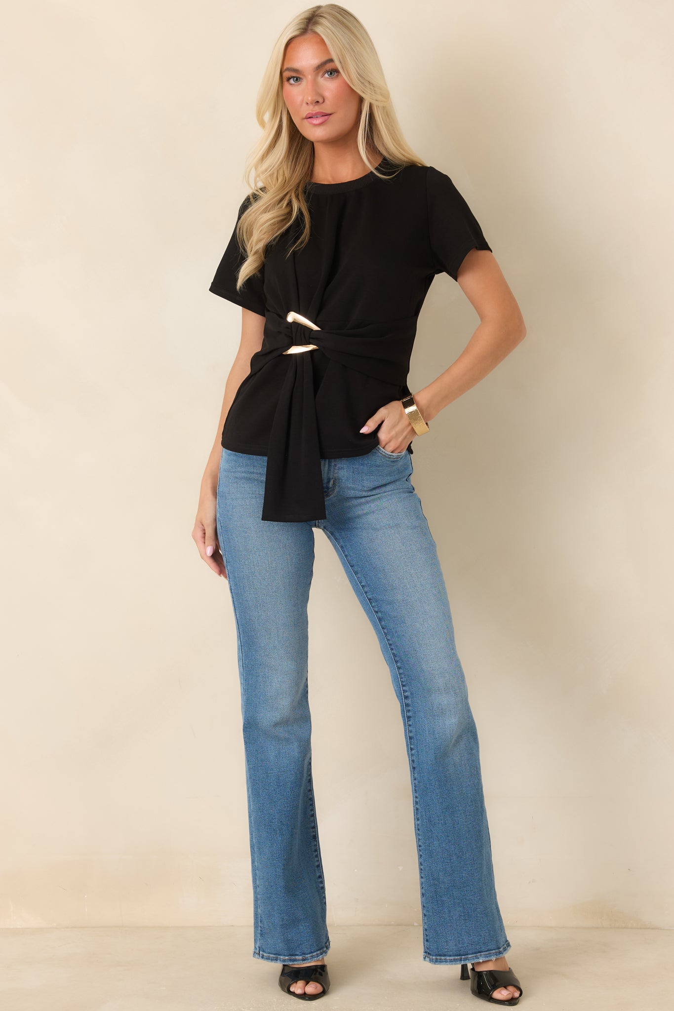 Short sleeve knit top featuring a crew neckline, gathered front detailing, and a sculptural gold-tone buckle.