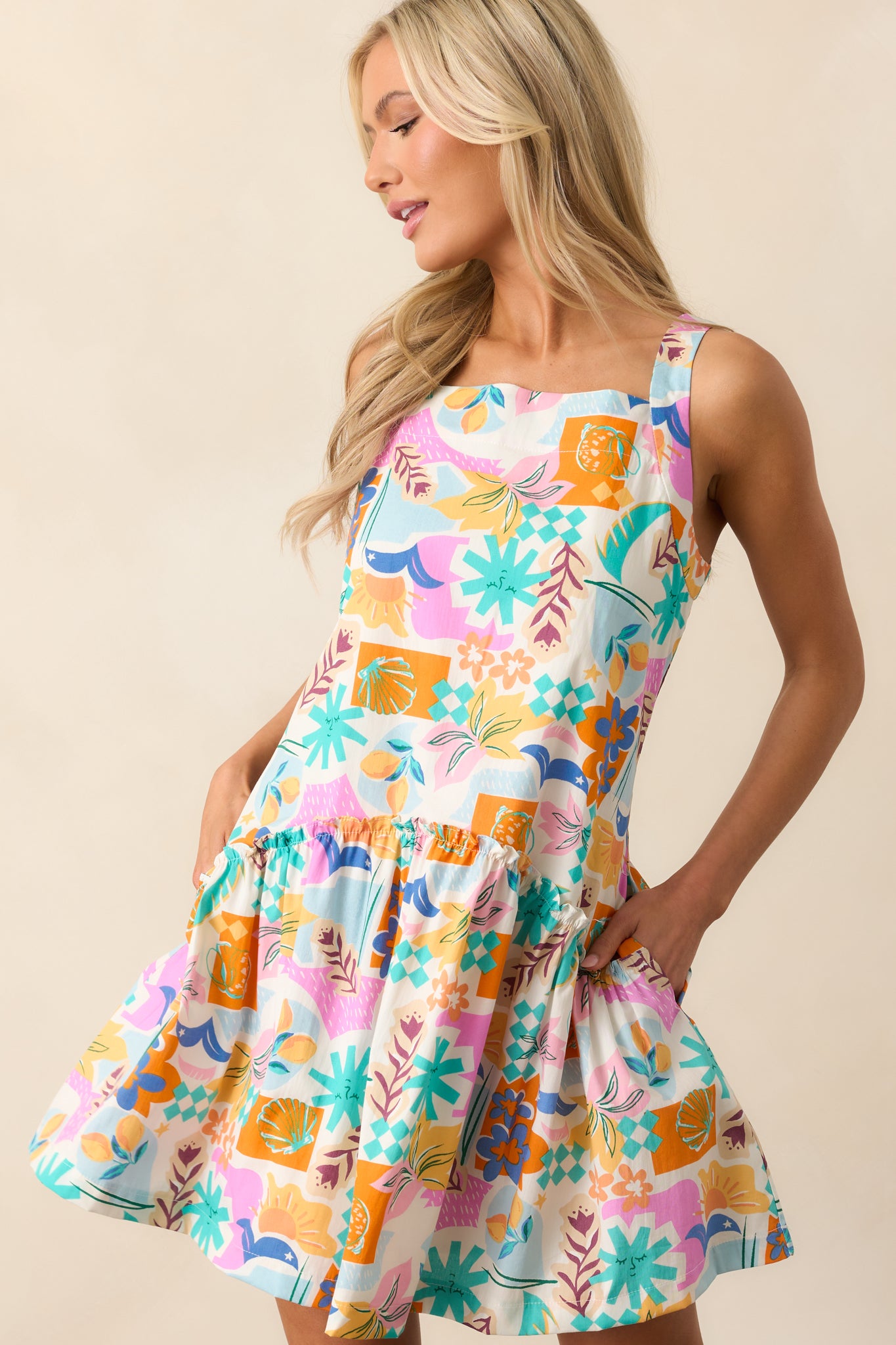 A detailed shot of the drop waist design and ruffle detailing on this pink dress, emphasizing the colorful tropical print and functional pockets for a fun, carefree look.
