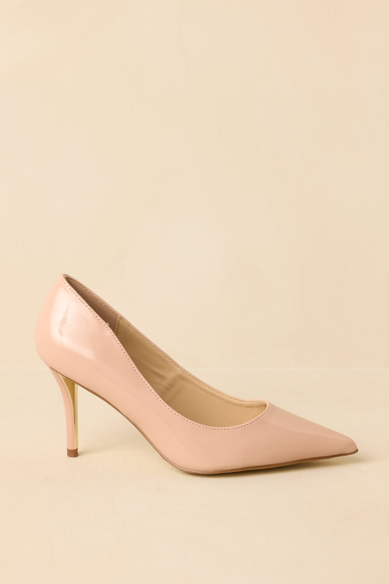 Side angle against a beige background emphasizing the slim stiletto heel and slip-on silhouette.