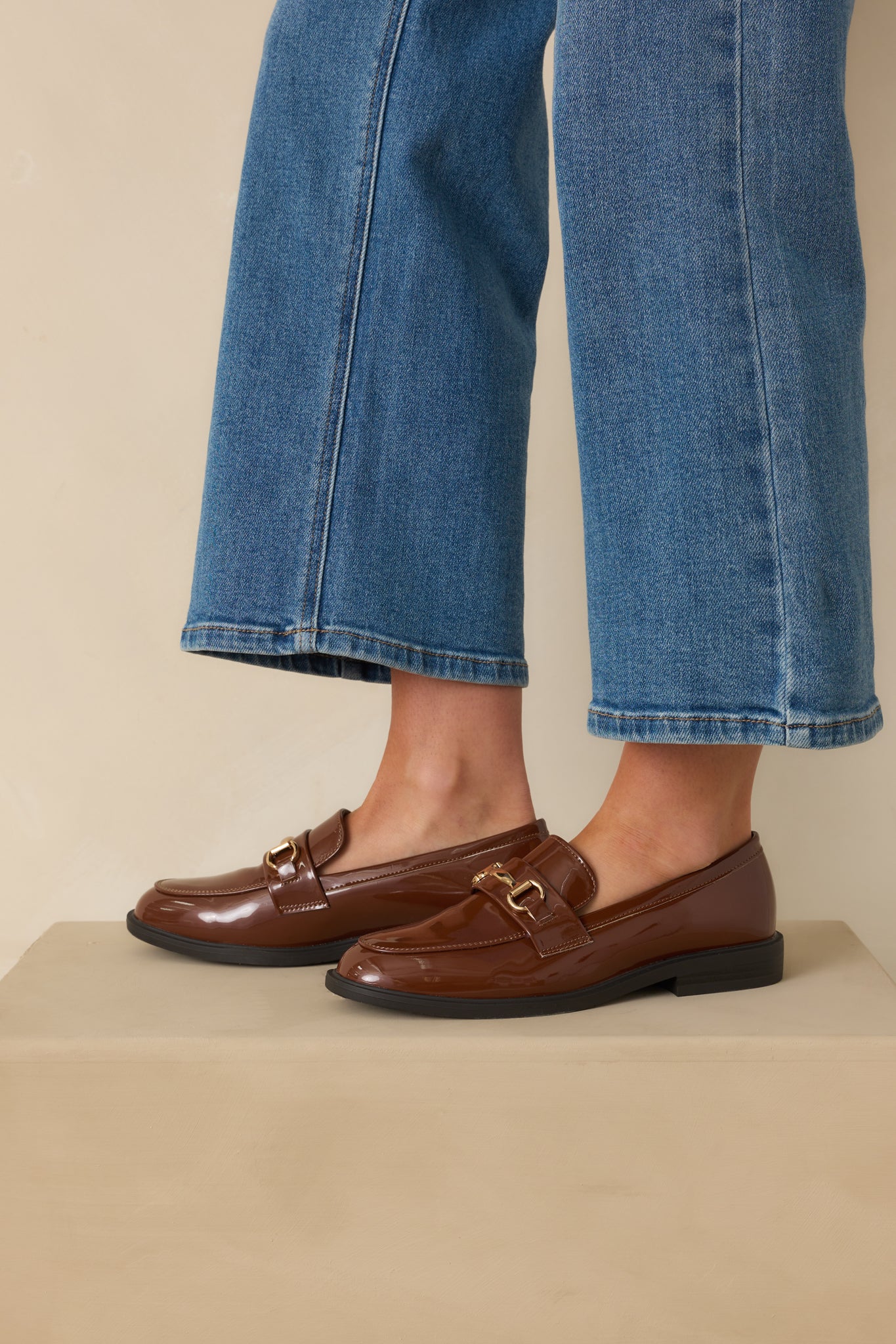 Side angle of loafers highlighting the low black stacked heel and topstitch accents.