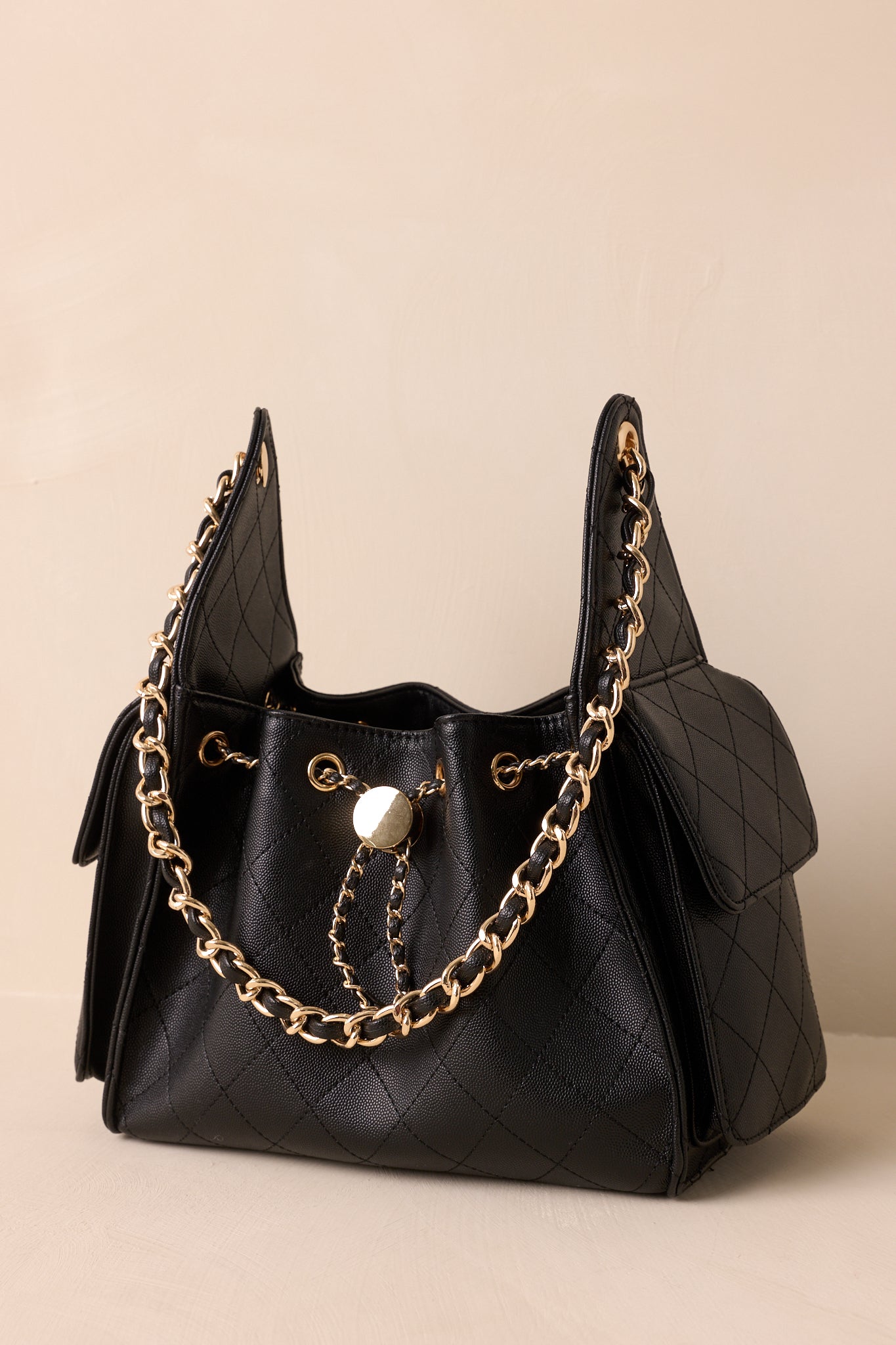 Side angle of the purse highlighting the structured silhouette and detachable faux leather cord and gold chain strap.