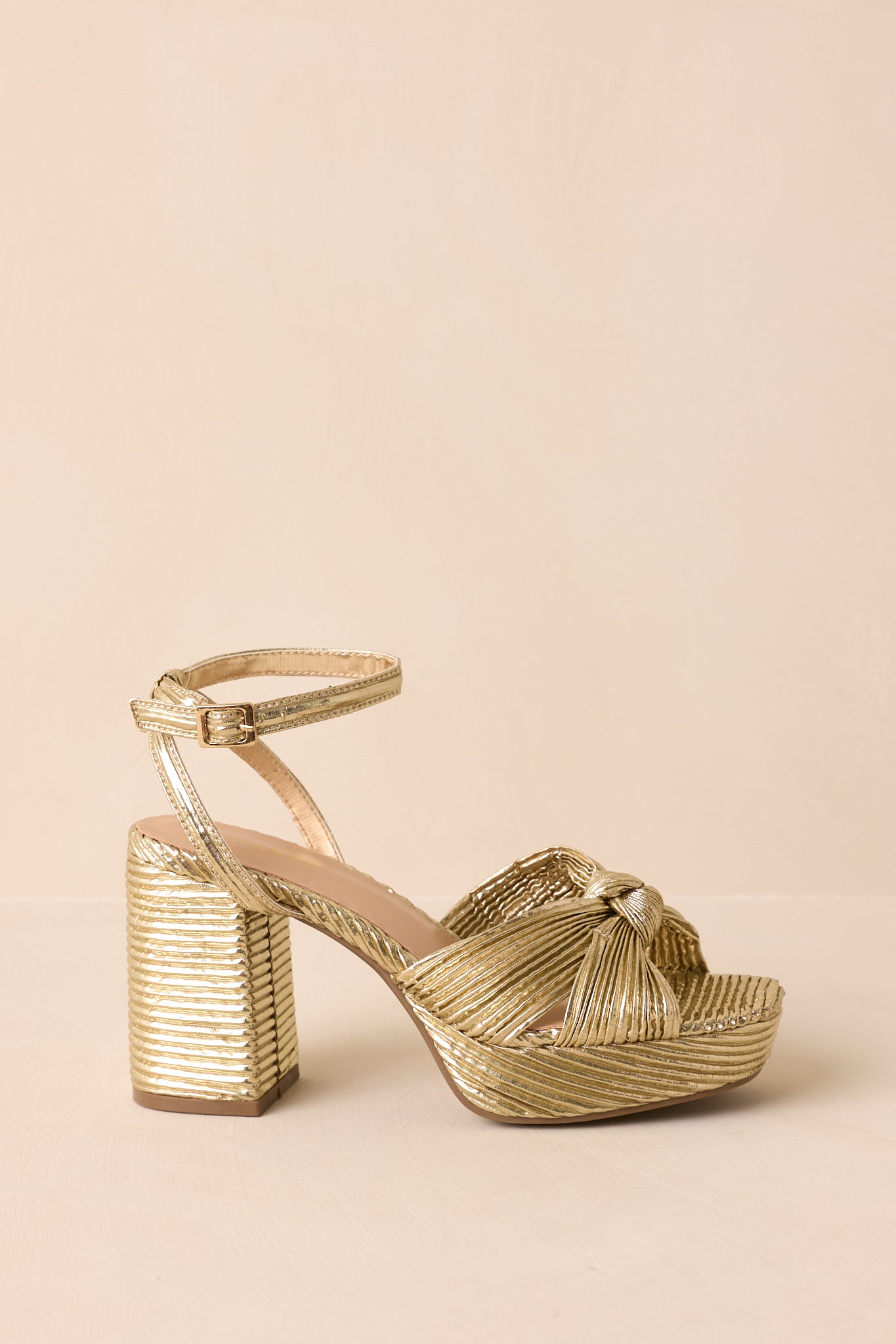 A side profile highlighting the ankle strap buckle, heel height, and pleated strap design.