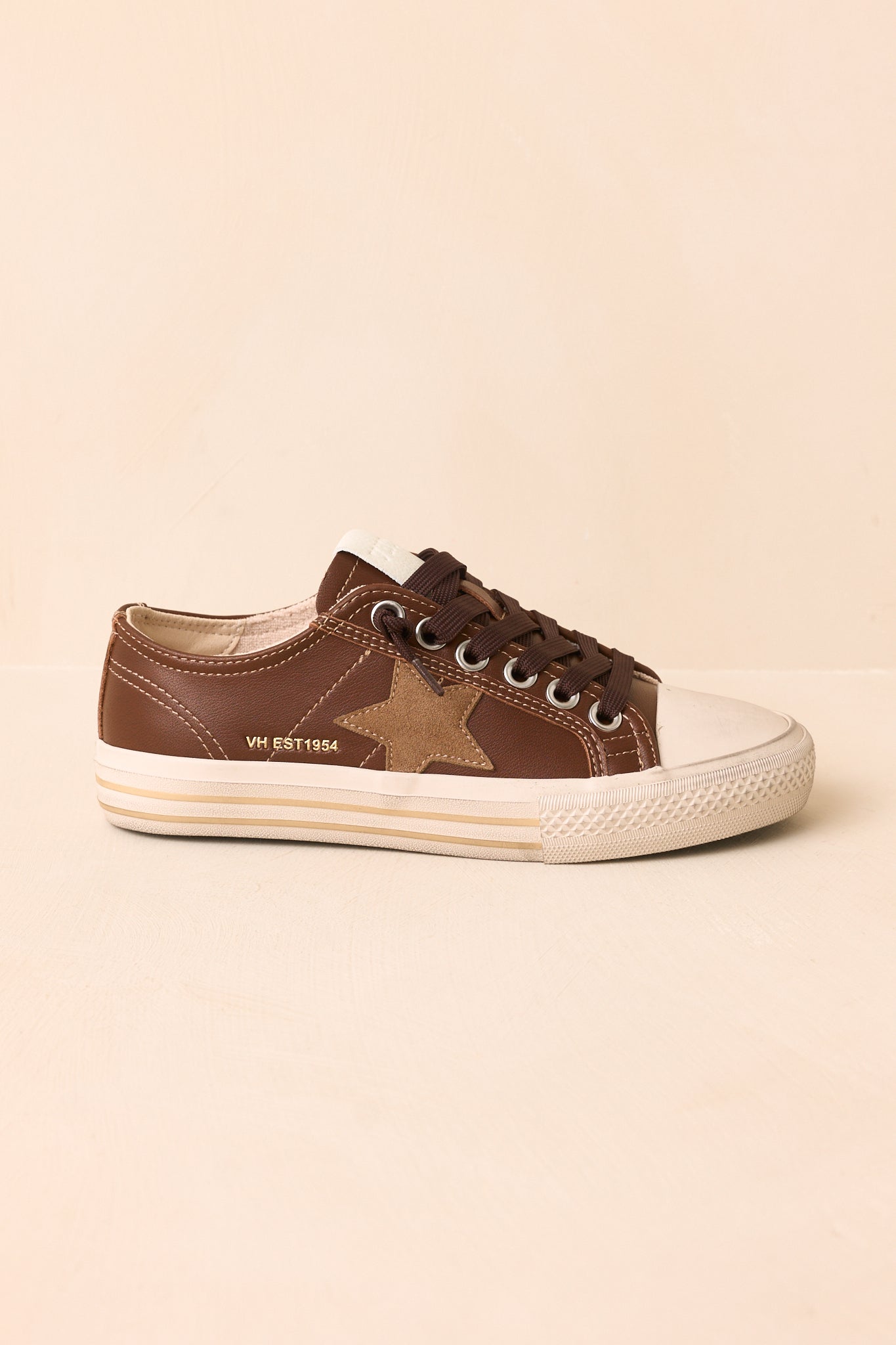 Side profile of the sneakers highlighting the taupe suede star and stacked rubber sole.