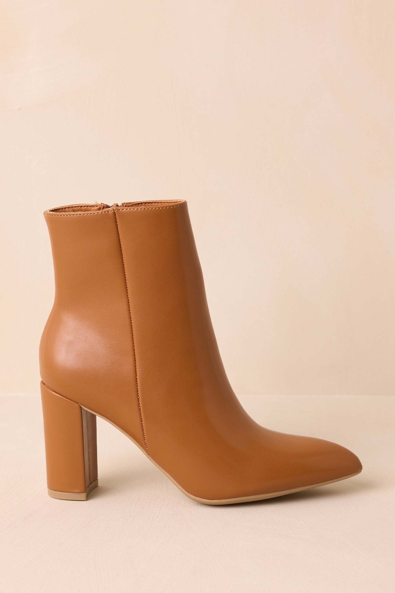 A side cropped view highlighting the outer seam detail on the caramel brown ankle boots.