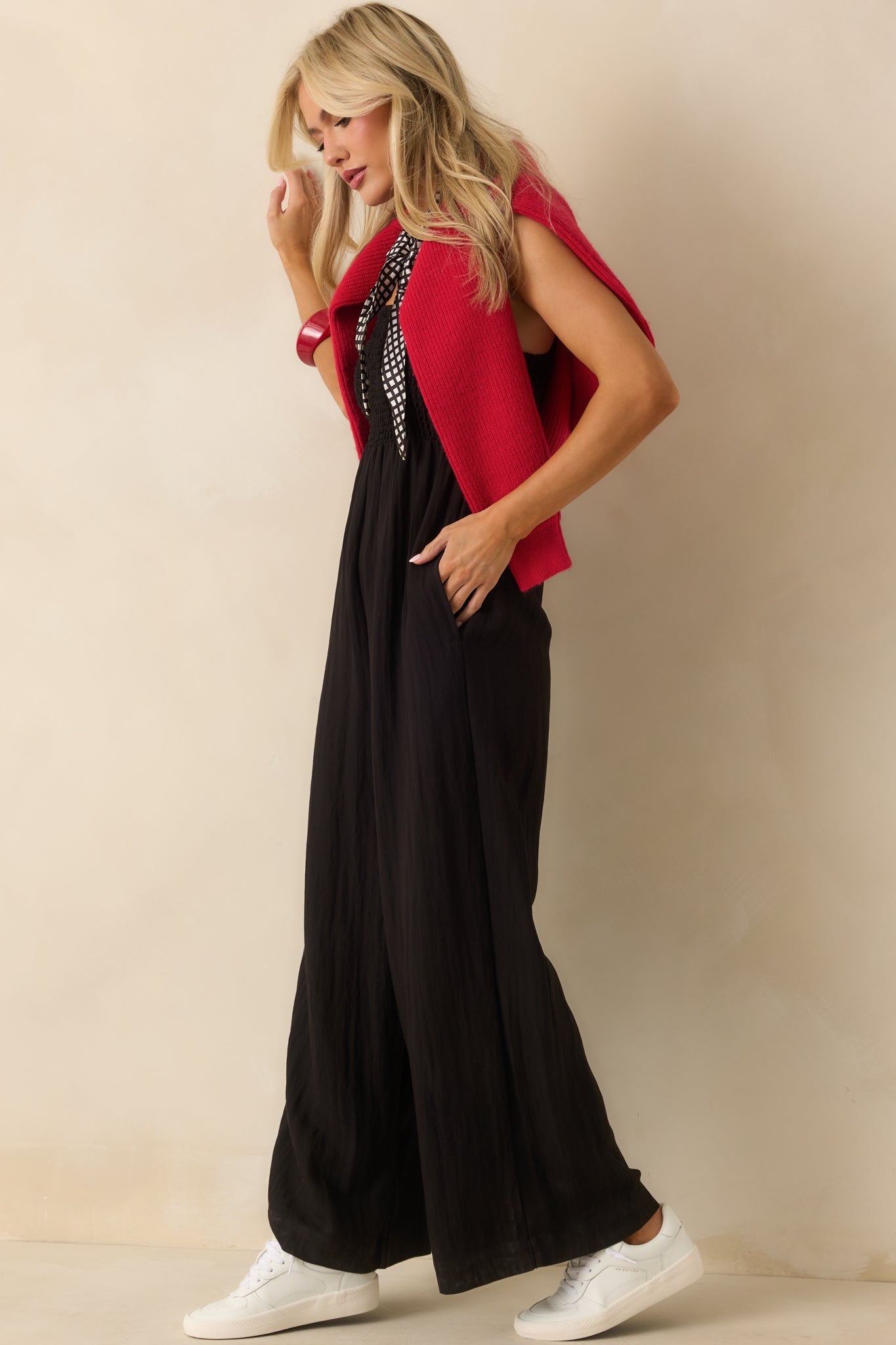 Full body side view of the black jumpsuit, emphasizing the functional side seam pocket and relaxed drape.