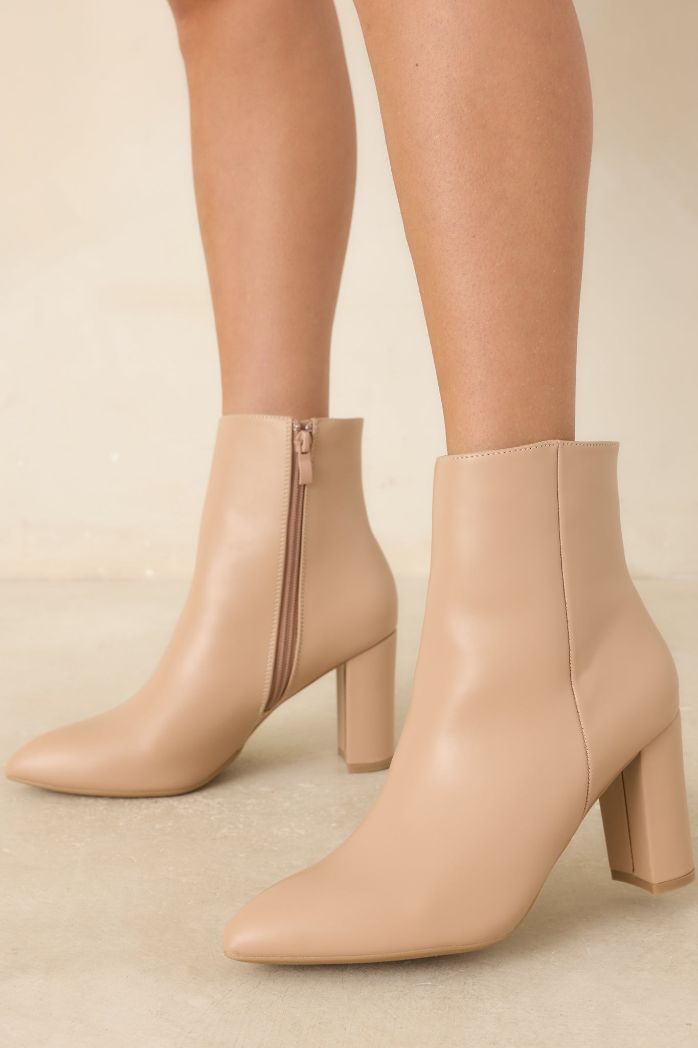 Side view of the beige ankle boots highlighting the pointed toe and sturdy block heel.