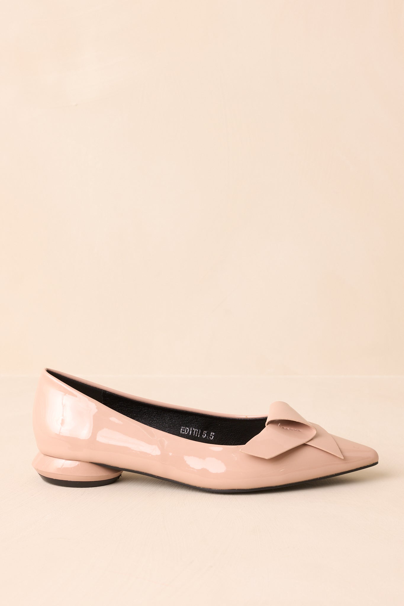 Side view of the beige patent flats on a beige background, highlighting the pointed toe and structured design.