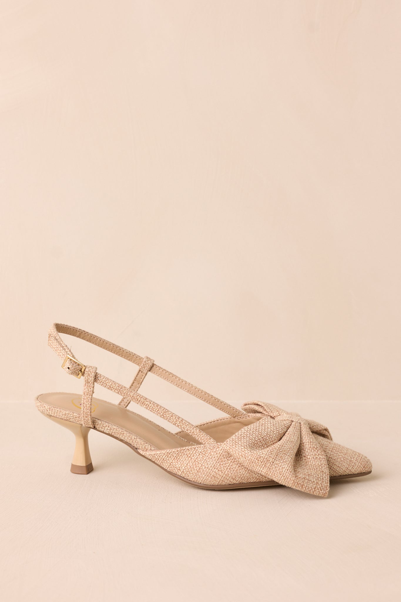 A side view of the heel, emphasizing the ankle strap with a gold buckle and the small kitten heel design.