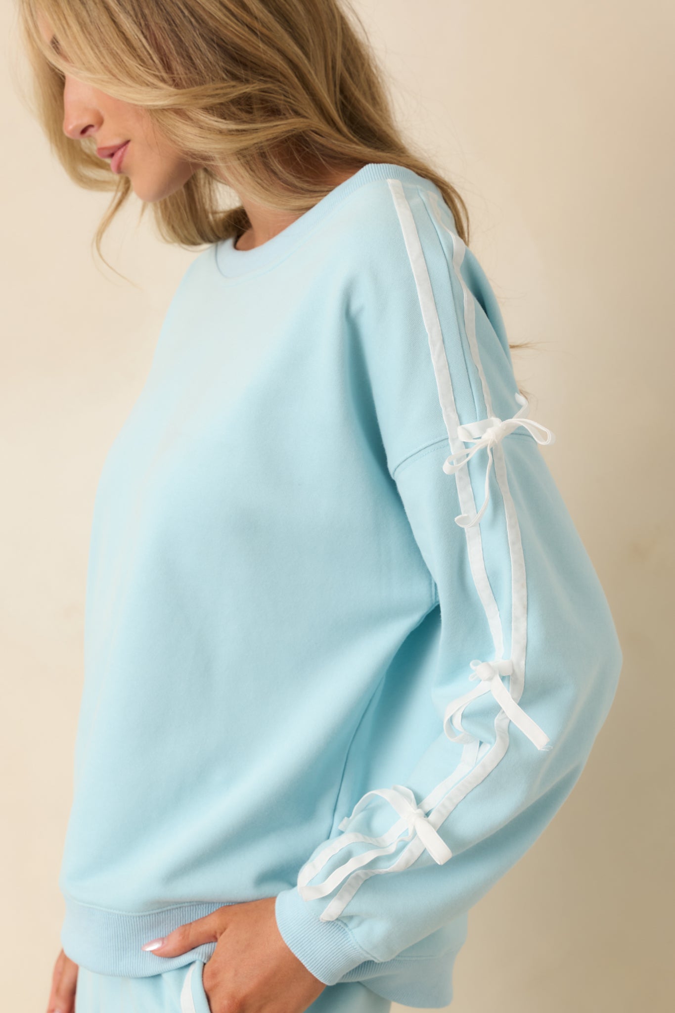 Side view of aqua sweatshirt showing sleeve tie detail and relaxed silhouette.