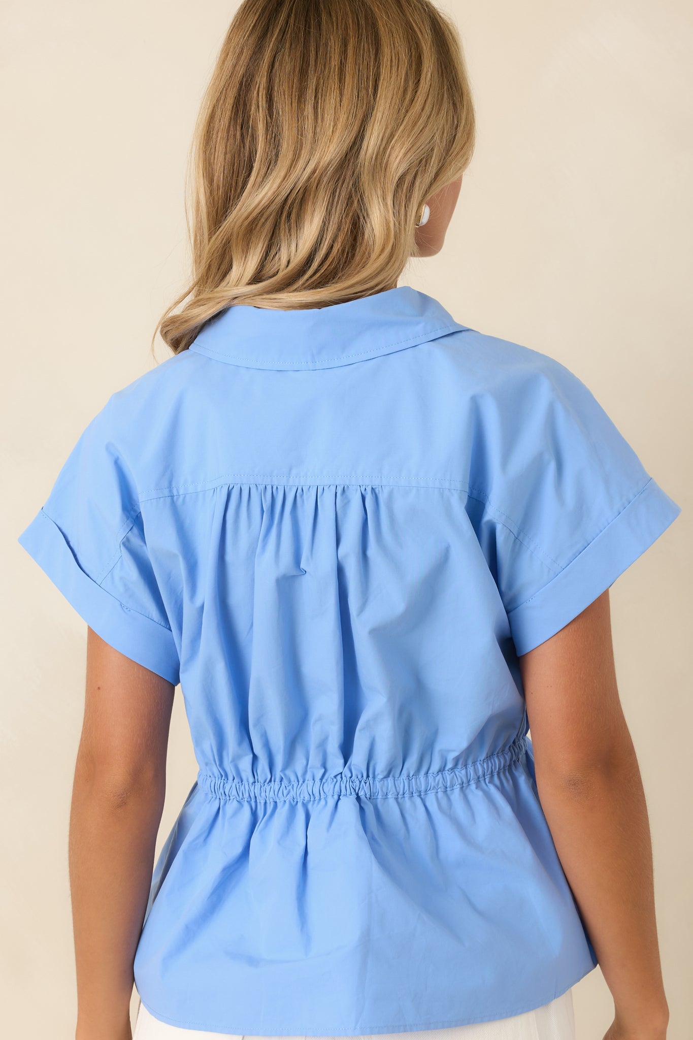 Rear view of the sky blue cotton top featuring relaxed cap sleeves, a softly gathered peplum hem, and a comfortable adjustable waist for a flattering finish.