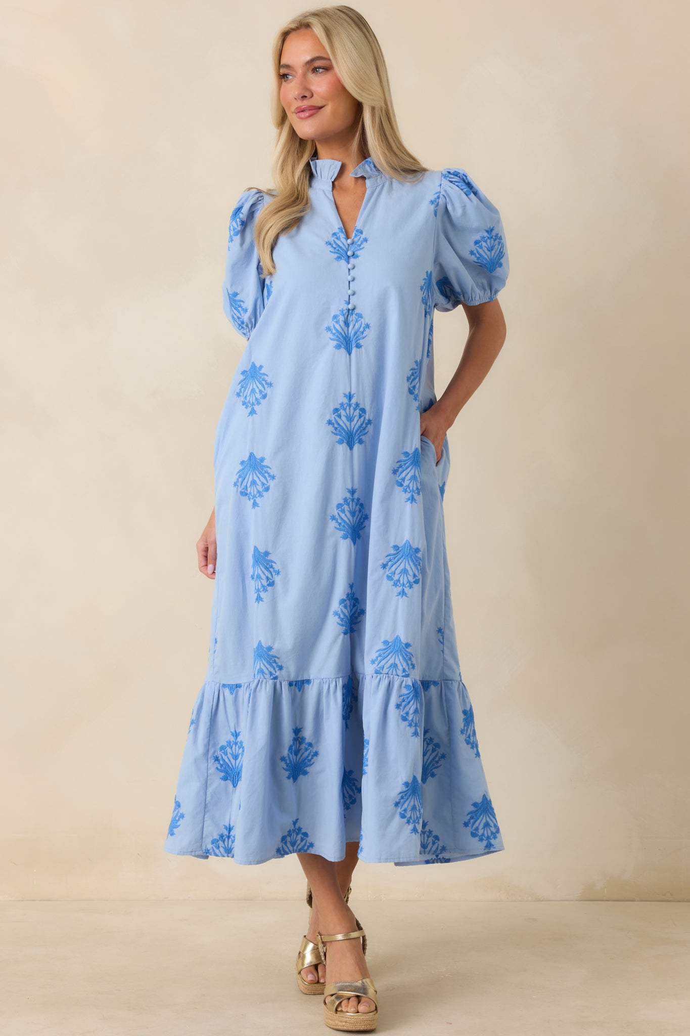 Cotton sky blue dress with a gently ruffled neckline, split front opening, covered button accents, and an easy flowing silhouette.