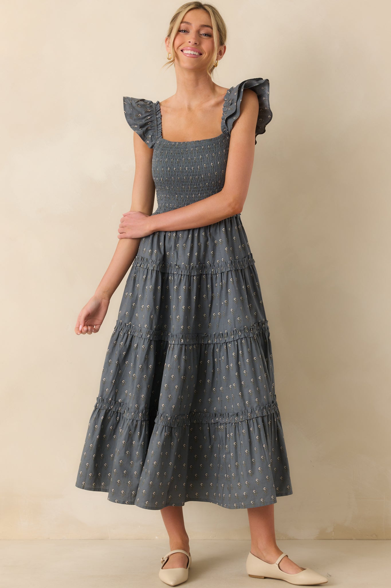 Slate blue floral dress with a tiered skirt and flowy, feminine silhouette.