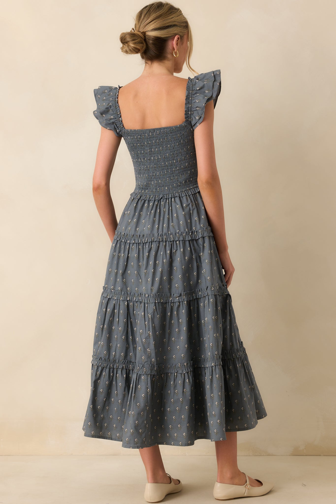 Rear view of slate blue midi dress with ivory florals, smocked fit, and tiered ruffle skirt.