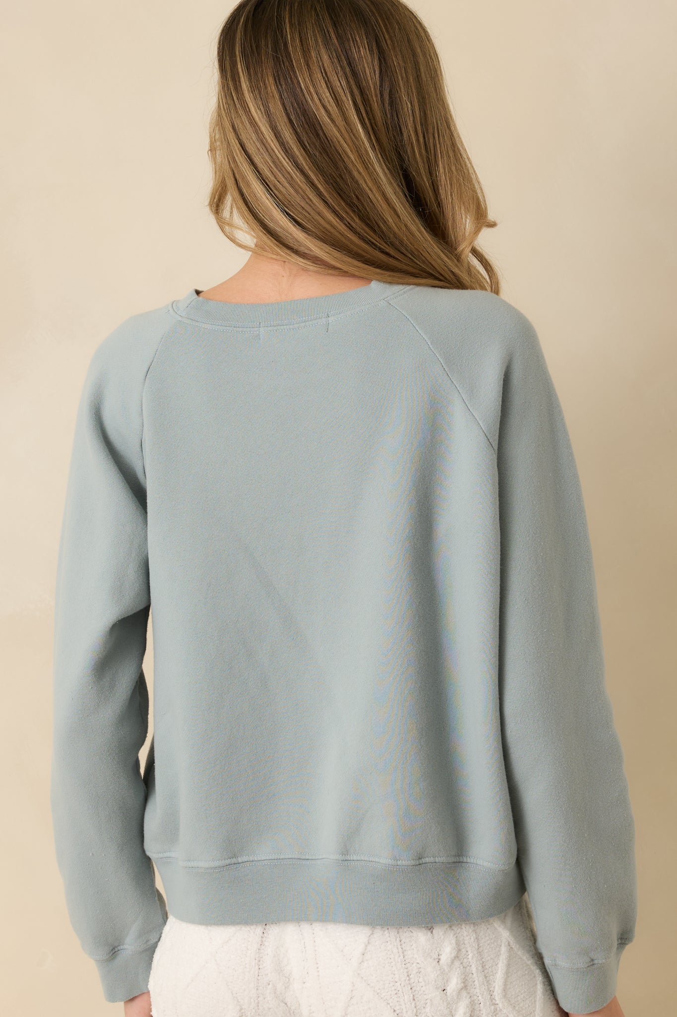 Slate blue sweatshirt showing smooth back fabric, raglan shaping, and ribbed trim.