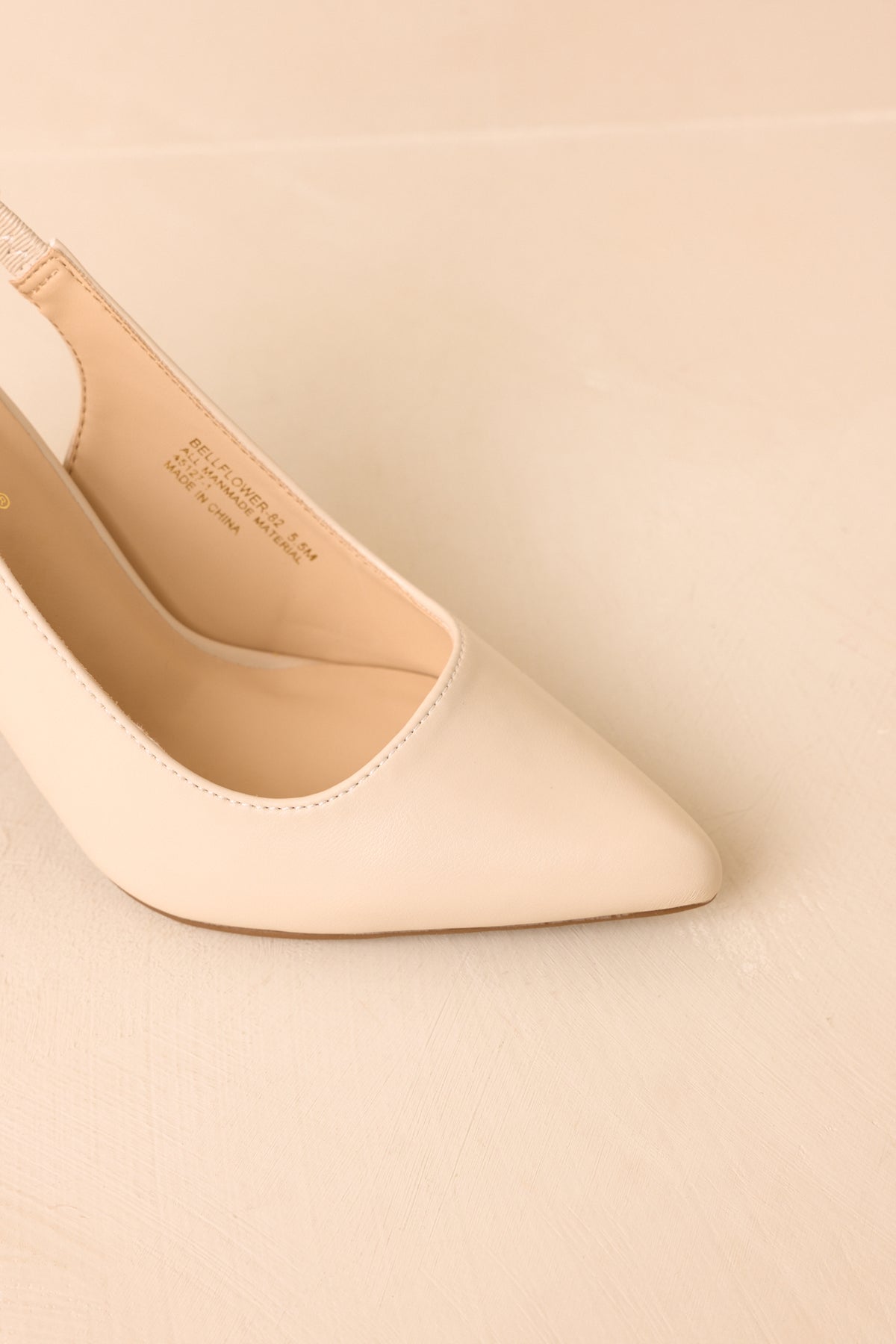 Sleek ivory slingback heels highlighting the refined pointed toe and elevated block heel profile.