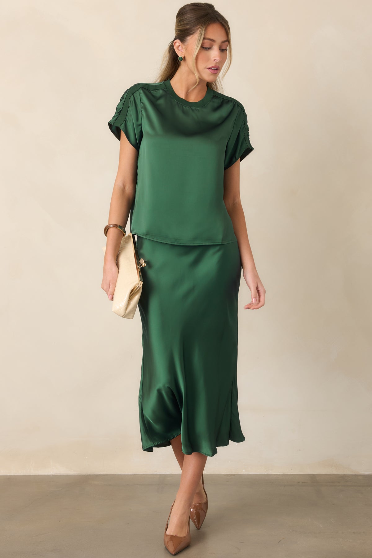 Sleek satin midi skirt showcasing its fluid drape, elasticized pull-on waistband, softly fitted hips, and elegant flared hem.