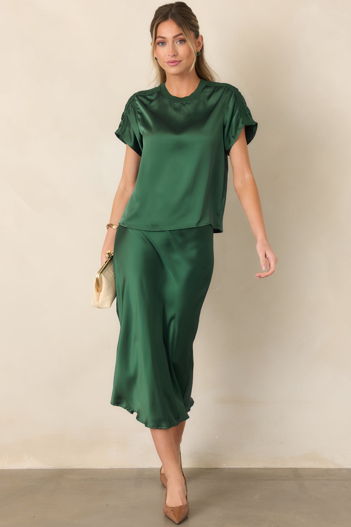 Sleek satin top defined by its fluid short-sleeve shape, round collar, softly reflective fabric, and contrasting textured trim.