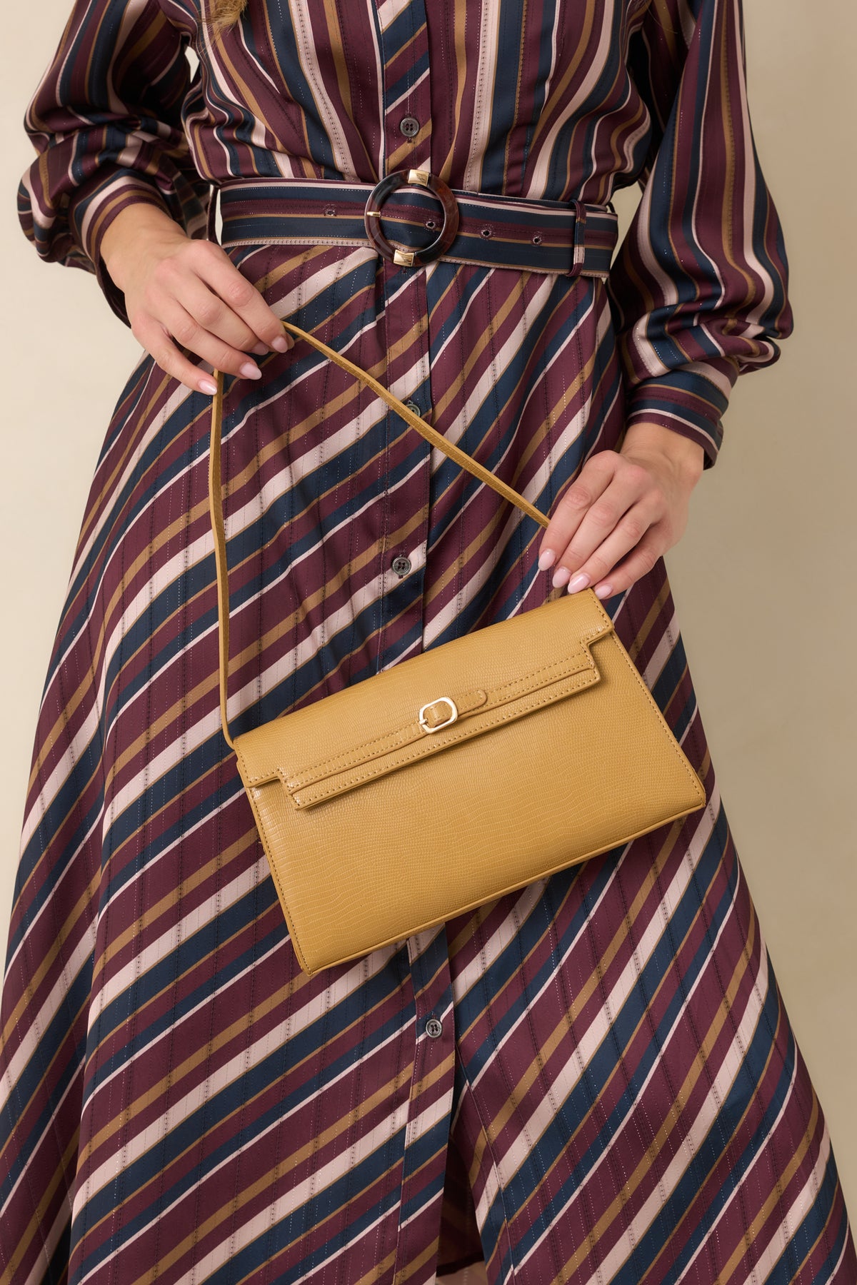 Sleek textured handbag with a structured envelope flap, delicate belt detail, gold-tone buckle, and thin strap.