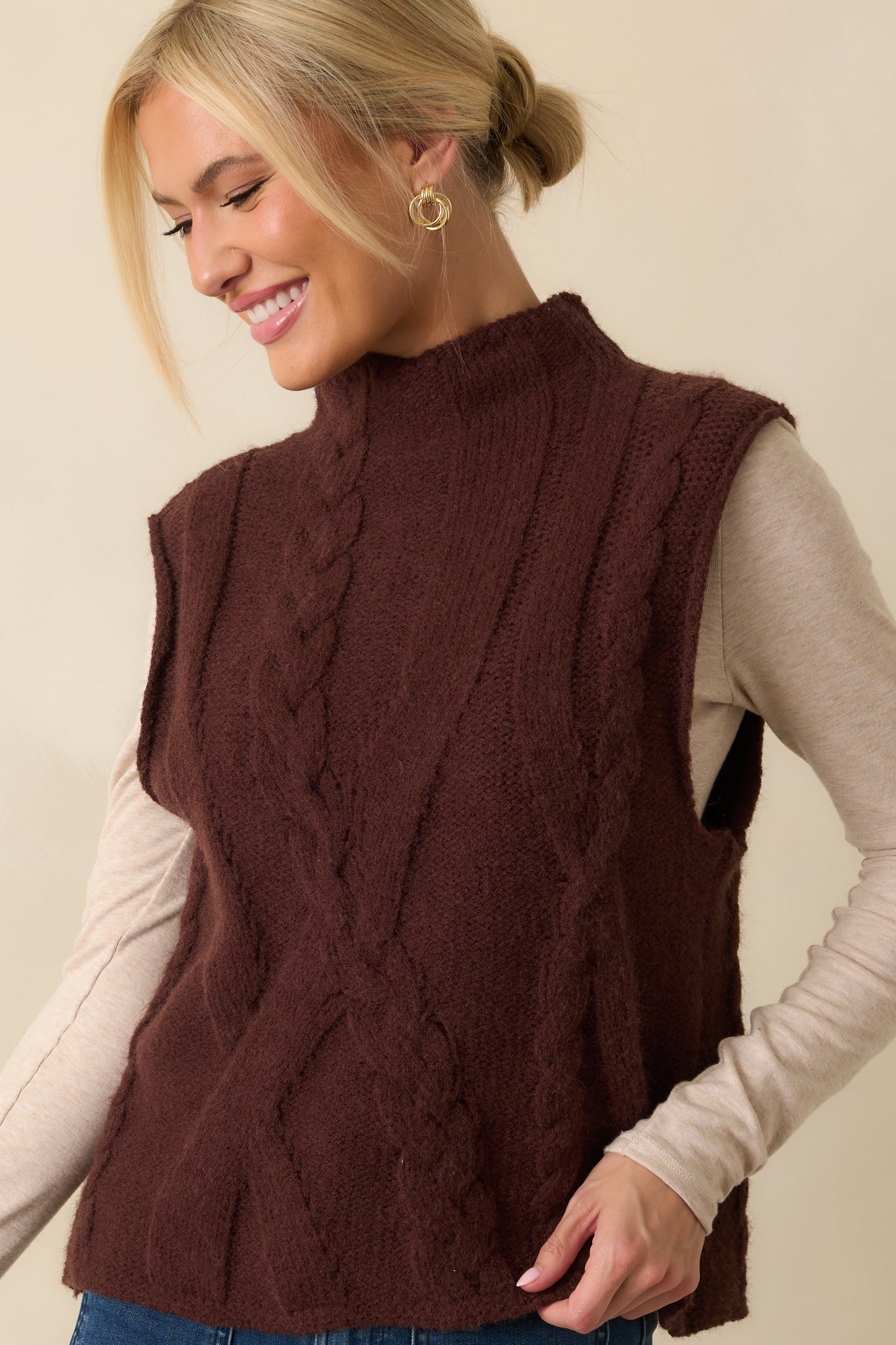 Focus on the sleeveless armhole and cable knit weave for a cozy layered look.