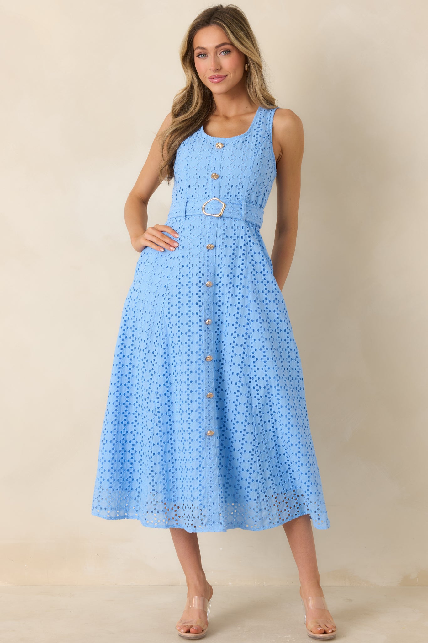 Sleeveless blue eyelet midi dress in breathable cotton featuring a defined waist tie and subtle button front detail